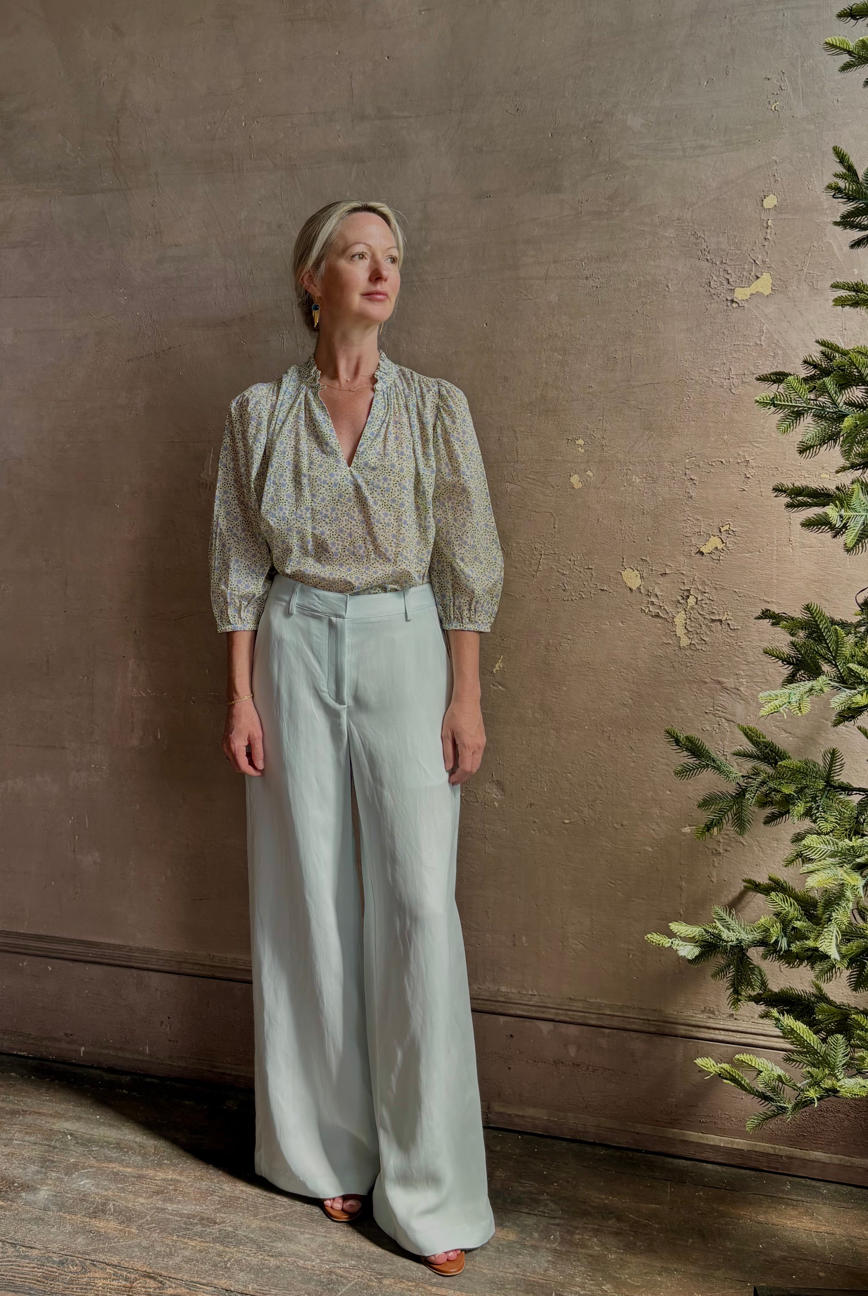 Mature woman wearing the Orly blouse from Trovata rendered in a charming coastal inspired floral print and crafted from cotton with three quarter sleeves and ruffle lined v-neck