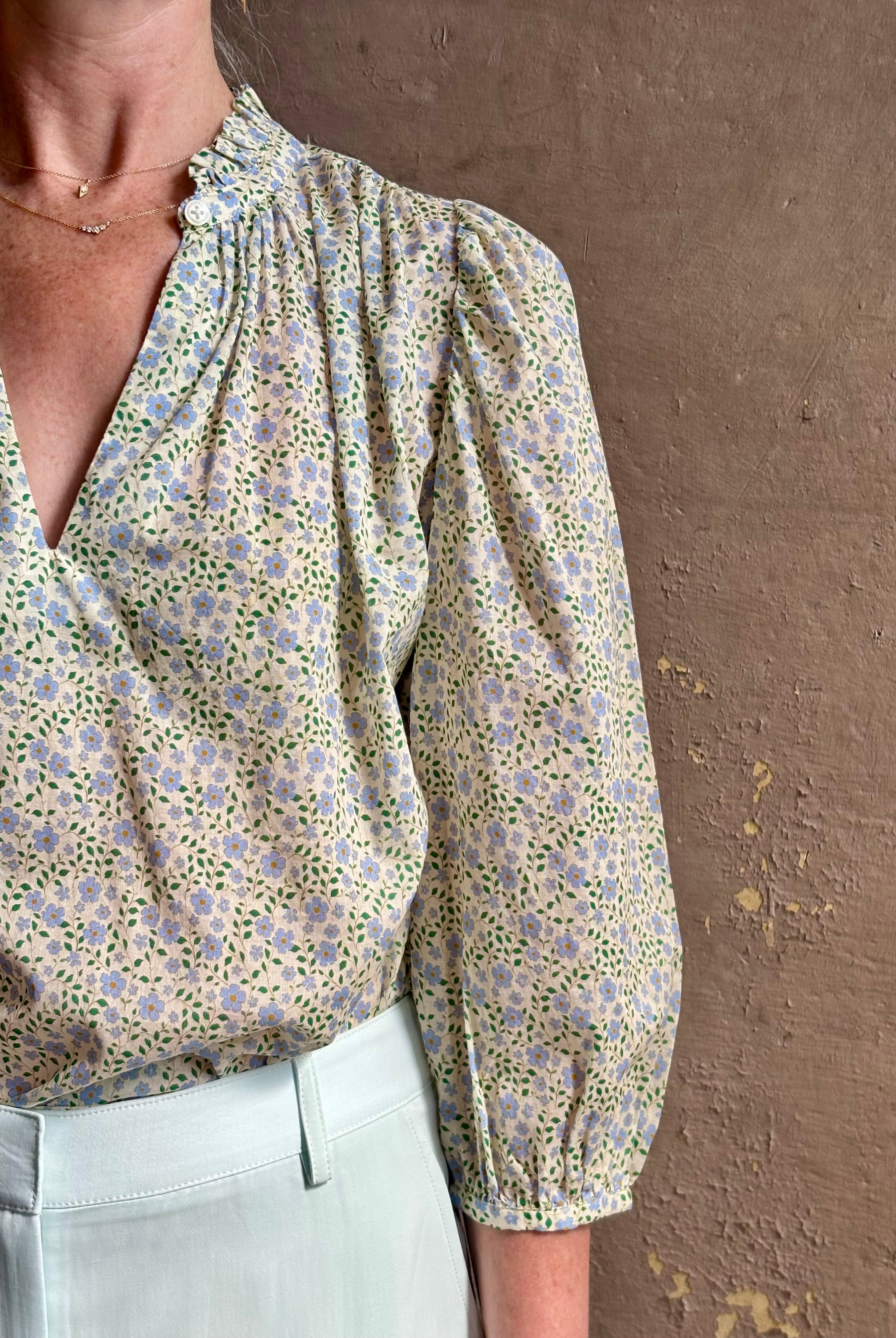 Mature woman wearing the Orly blouse from Trovata rendered in a charming coastal inspired floral print and crafted from cotton with three quarter sleeves and ruffle lined v-neck