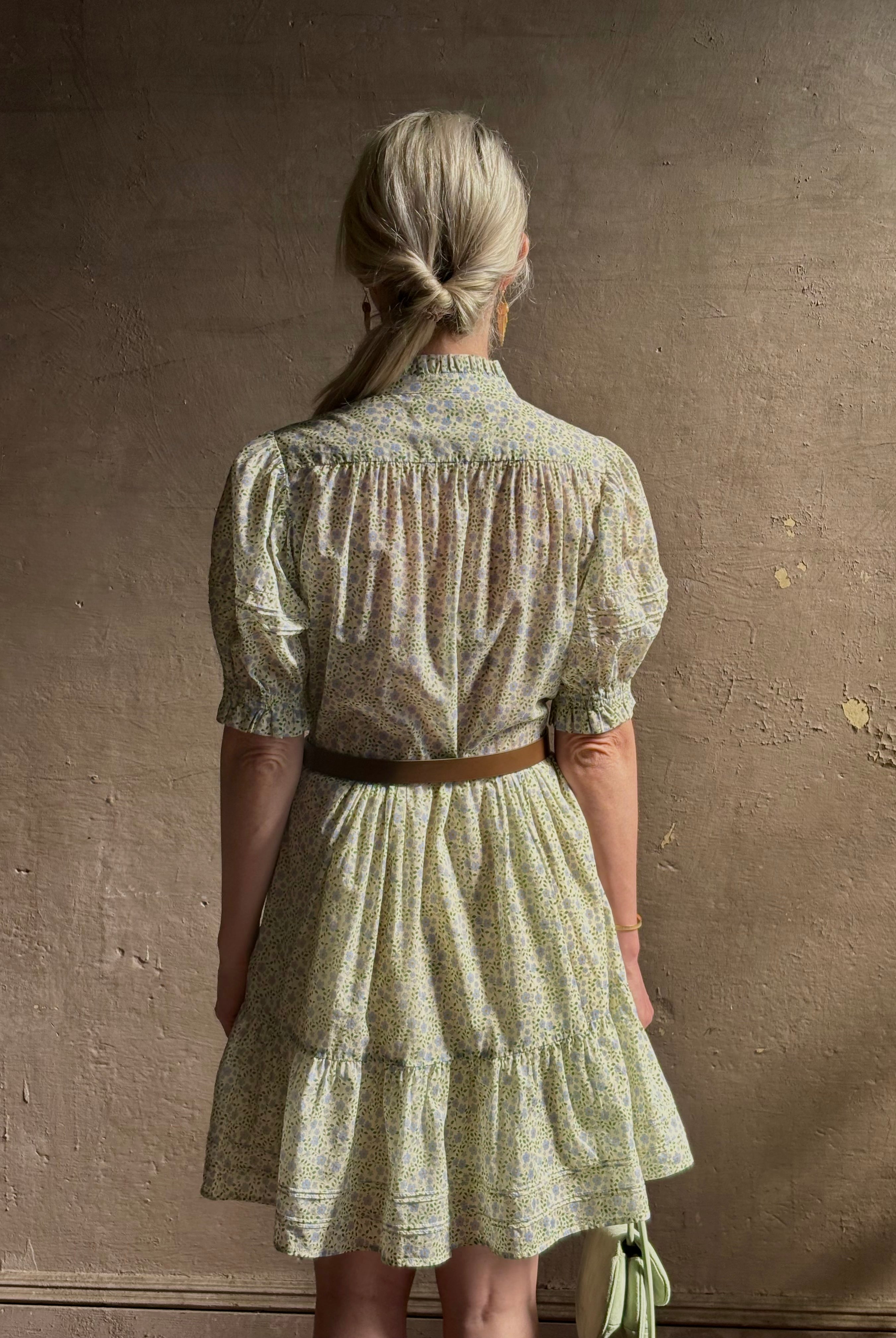 Mature woman wearing the short Phoebe Dress from Trovata rendered in a charming coastal inspired floral print and crafted from cotton with button front, ruffle lined short sleeves and v-neck