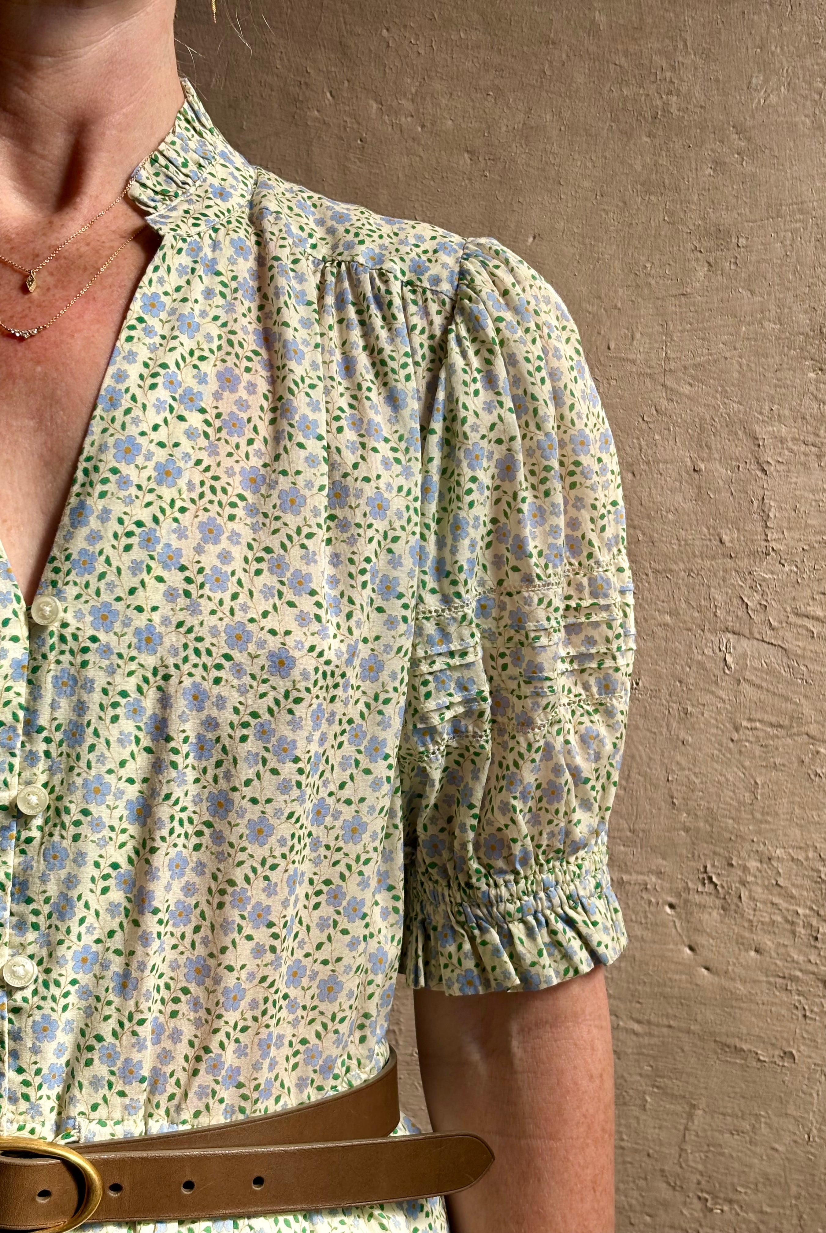 Mature woman wearing the short Phoebe Dress from Trovata rendered in a charming coastal inspired floral print and crafted from cotton with button front, ruffle lined short sleeves and v-neck