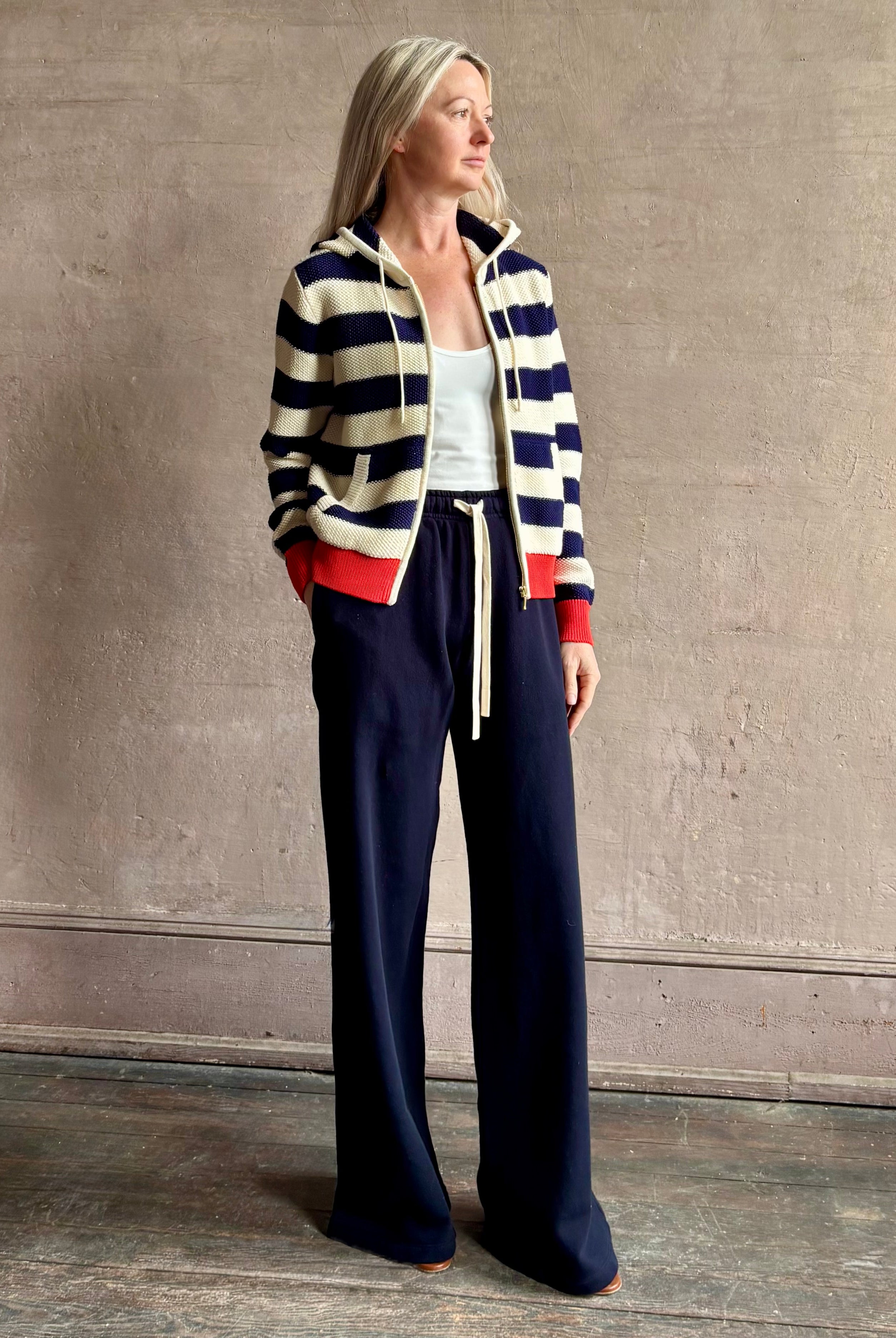 Mature woman wearing comfy cotton Rafa zip up hoodie by Trovata in a classic navy and white stripe with an elevated gold tone zipper.