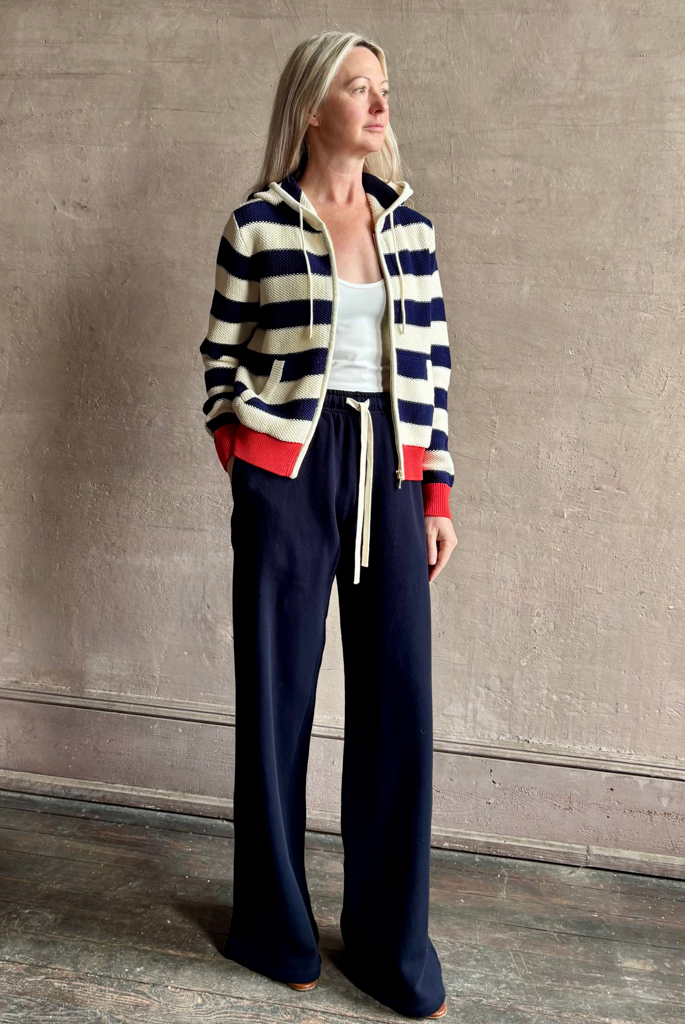 Mature woman wearing comfy cotton Rafa zip up hoodie by Trovata in a classic navy and white stripe with an elevated gold tone zipper.