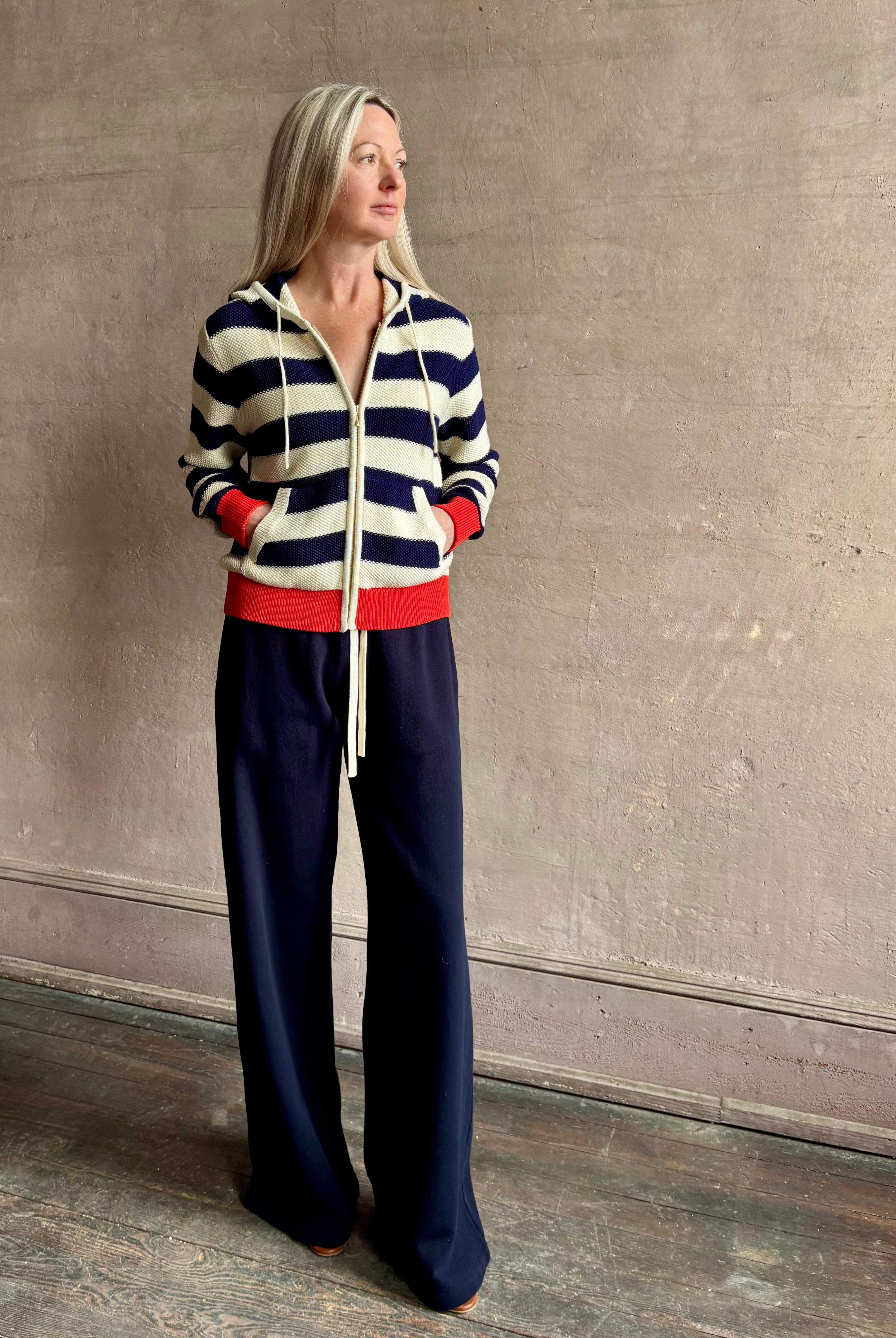 Mature woman wearing comfy cotton Rafa zip up hoodie by Trovata in a classic navy and white stripe with an elevated gold tone zipper.