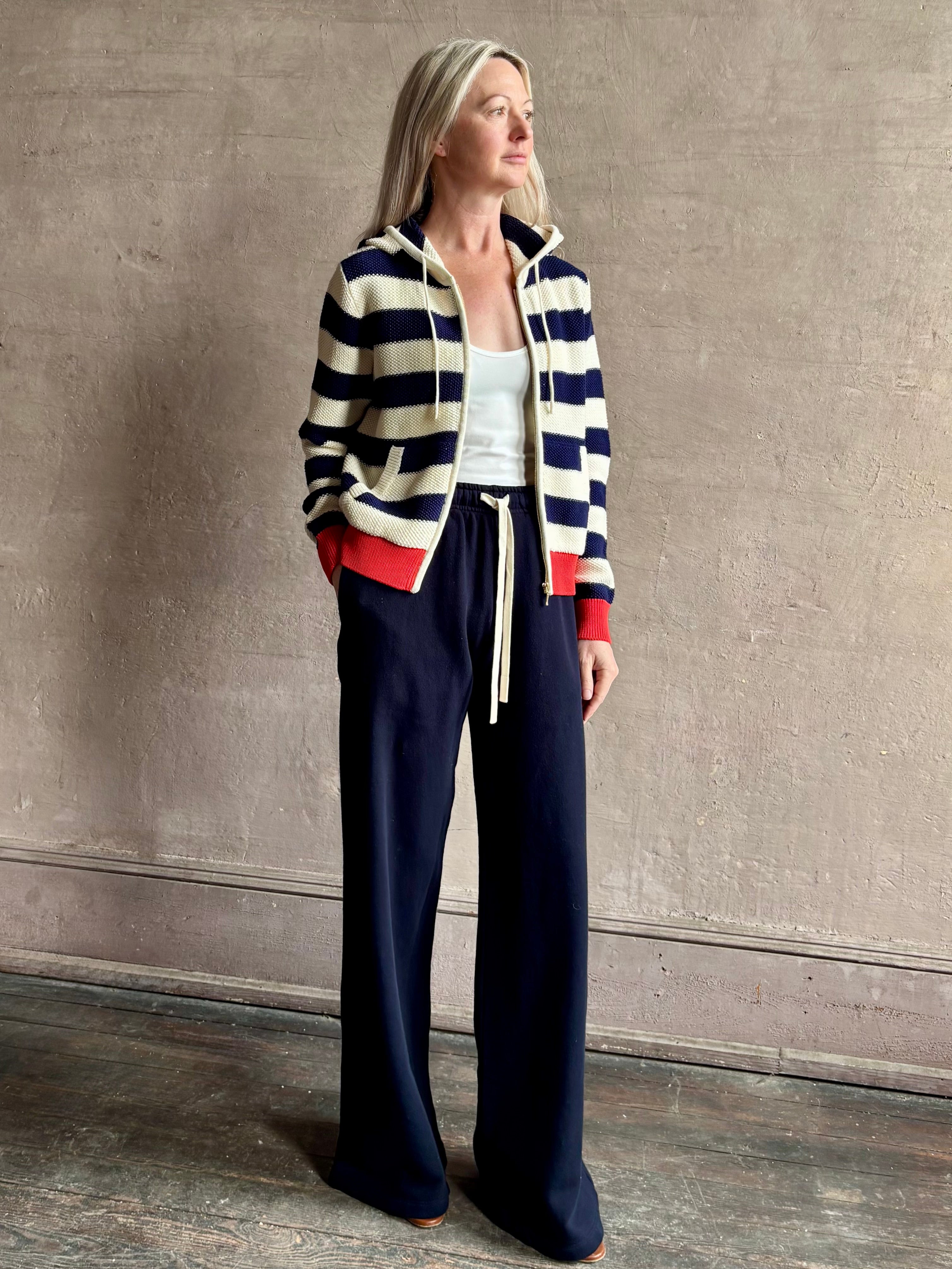 Mature woman wearing comfy cotton Rafa zip up hoodie by Trovata in a classic navy and white stripe with an elevated gold tone zipper.