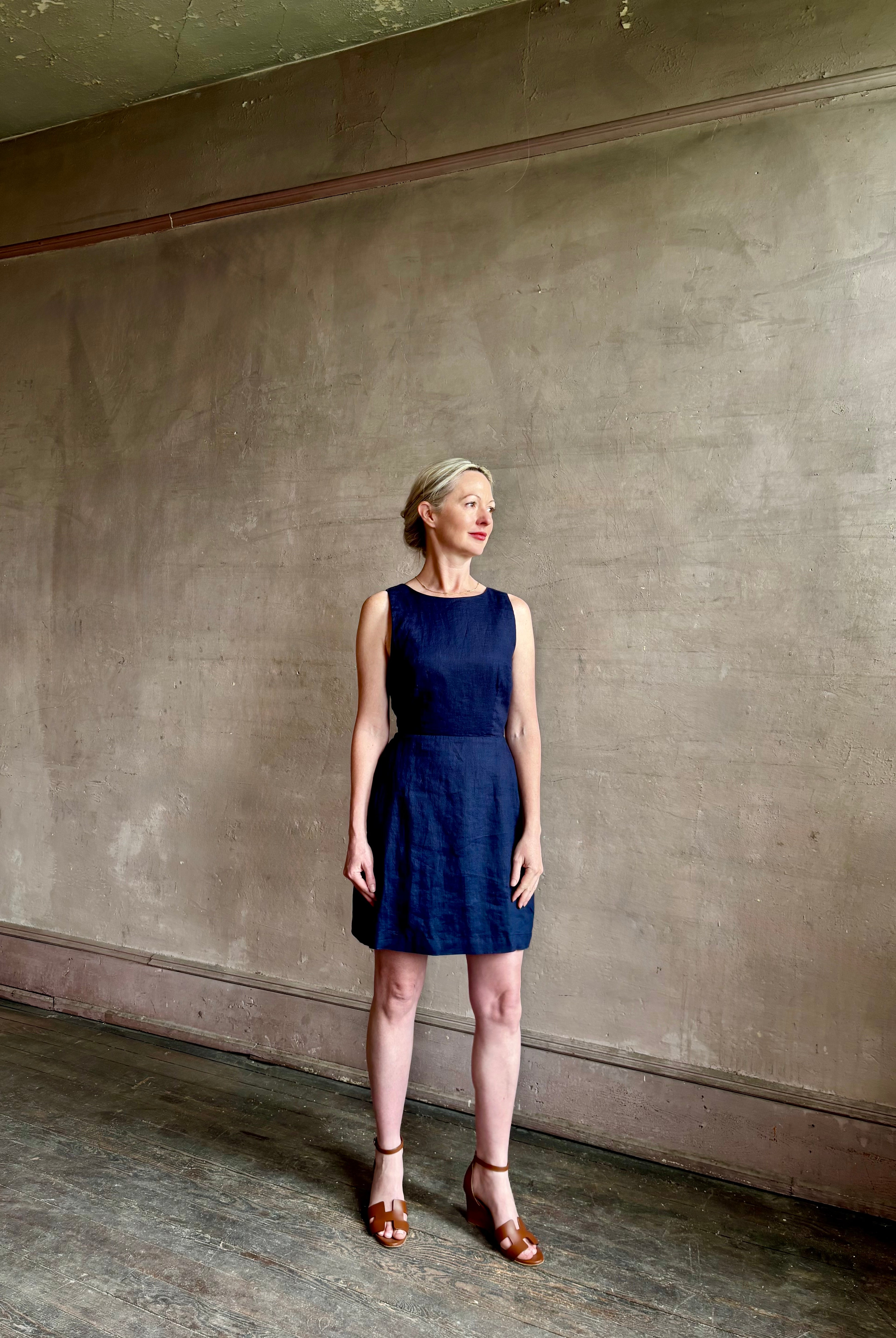 Woman wearing the effortless summer dress by Trovata Rosalie linen Dress in Navy Blue with A-line skirt and sophisticated bra friendly open back