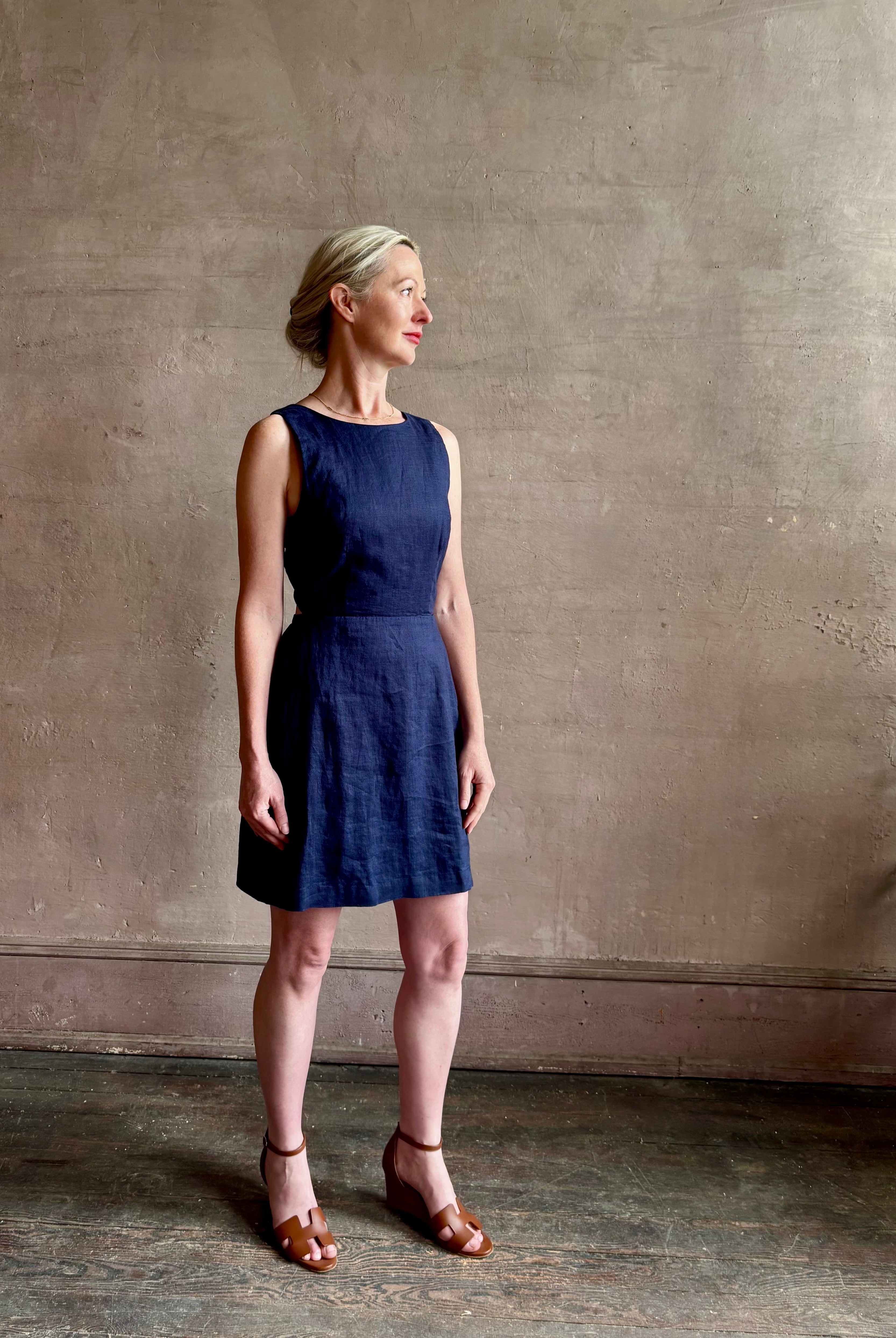 Woman wearing the effortless summer dress by Trovata Rosalie linen Dress in Navy Blue with A-line skirt and sophisticated bra friendly open back