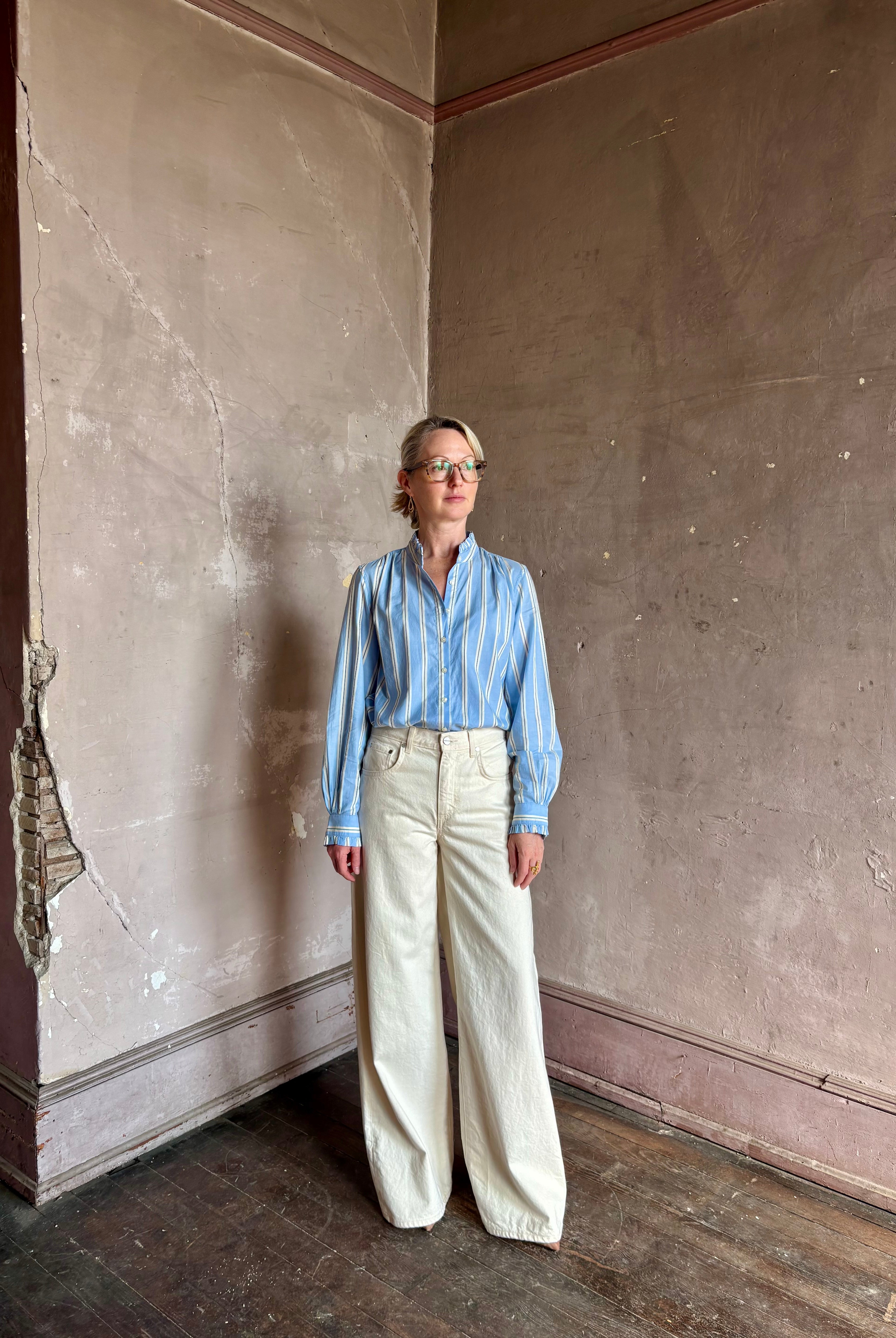 Mature woman wearing blue and cream vertically striped long-sleeve cotton Trovata Rumi button front shirt