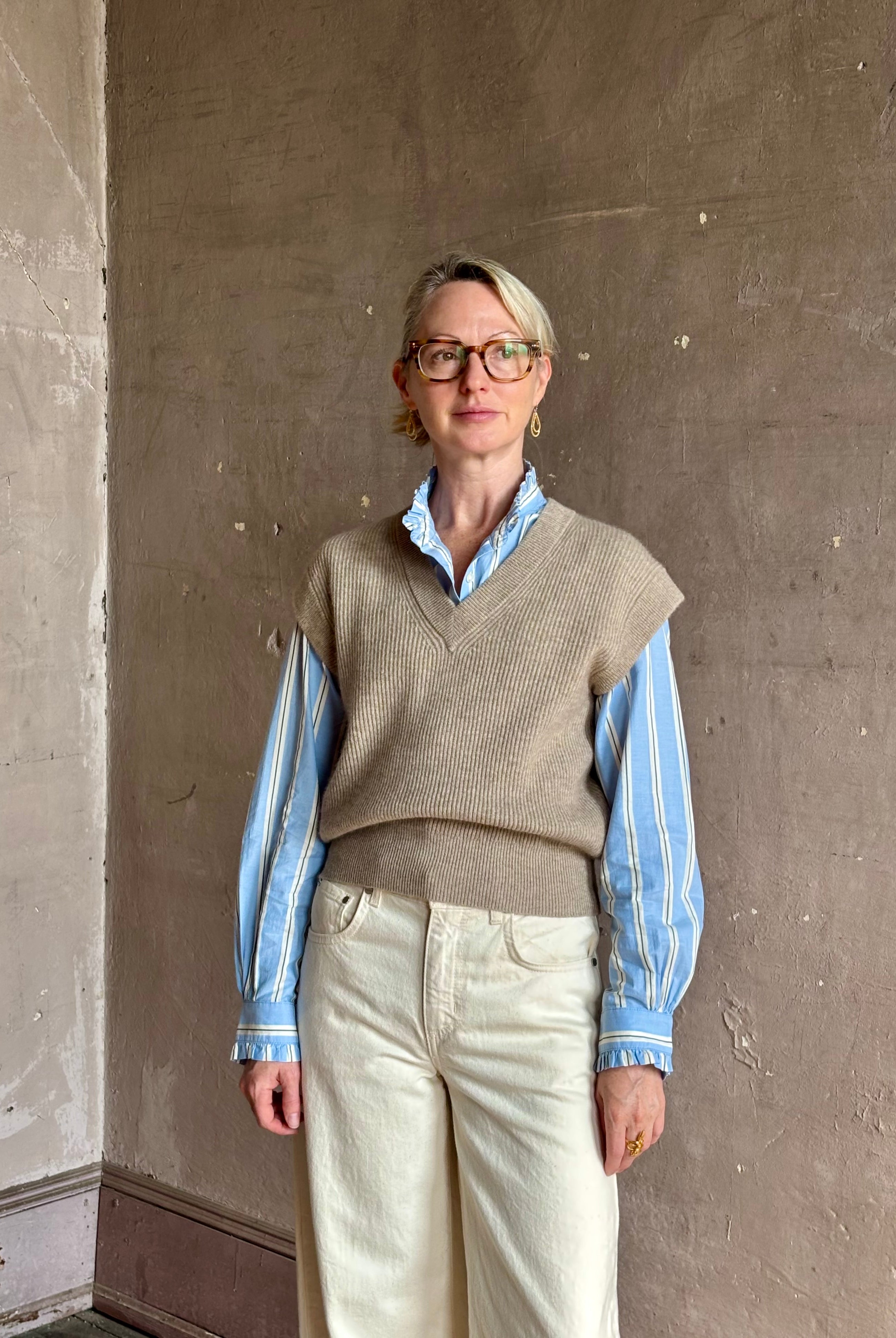 Mature woman wearing beige knit sweater vest over a blue and white striped button-down Trovata Rumi shirt