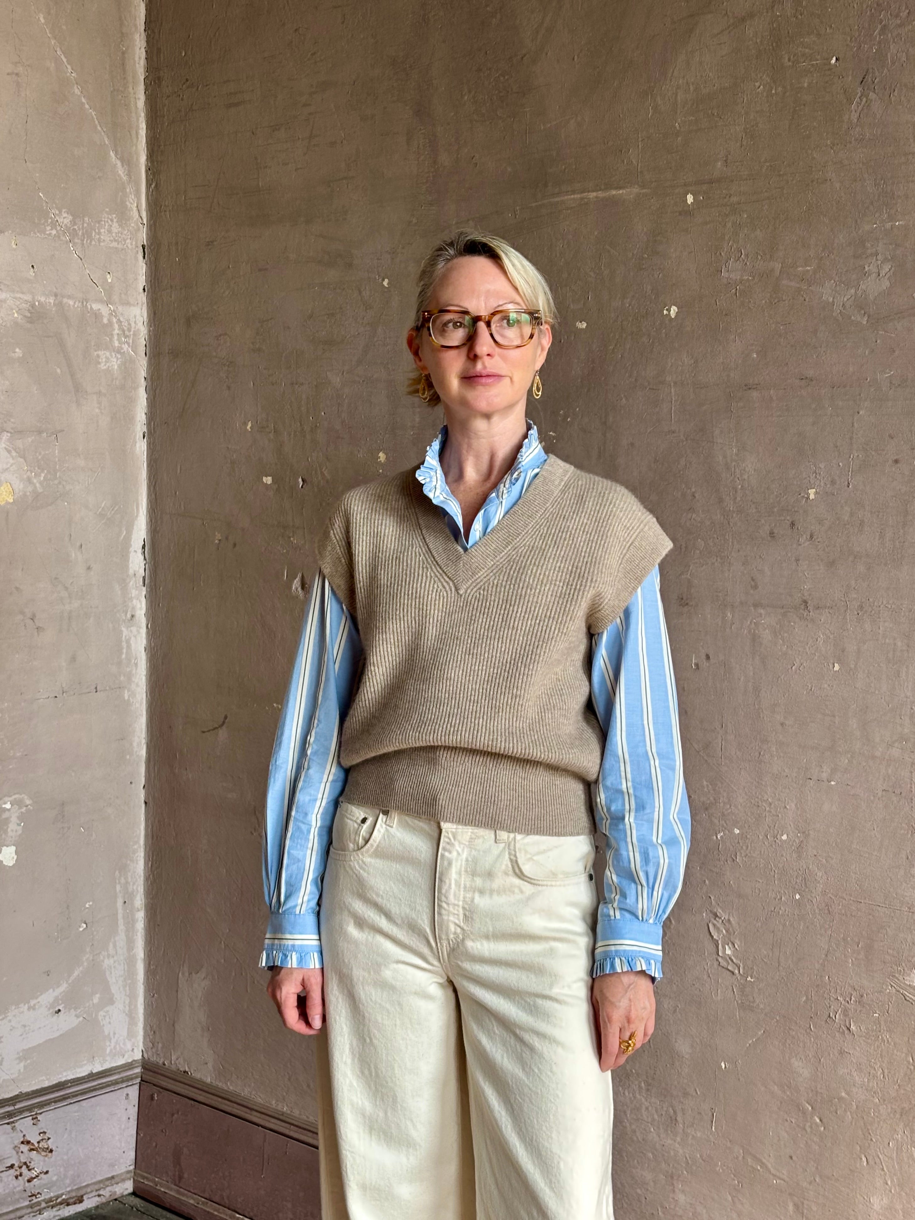 Mature woman wearing beige knit sweater vest over a blue and white striped button-down Trovata Rumi shirt