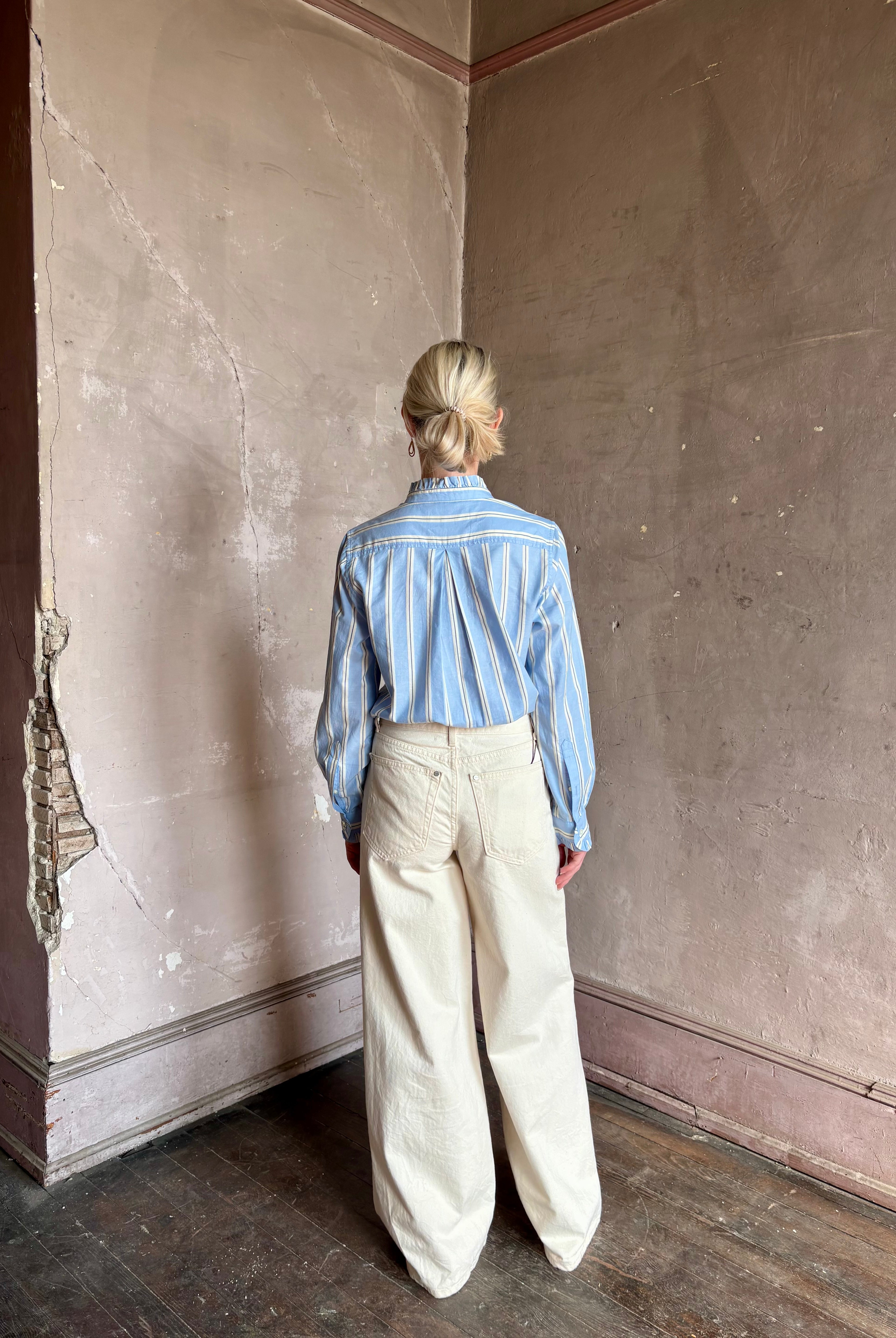 Mature woman wearing blue and cream vertically striped long-sleeve cotton Trovata Rumi shirt ruffle lined cuffs