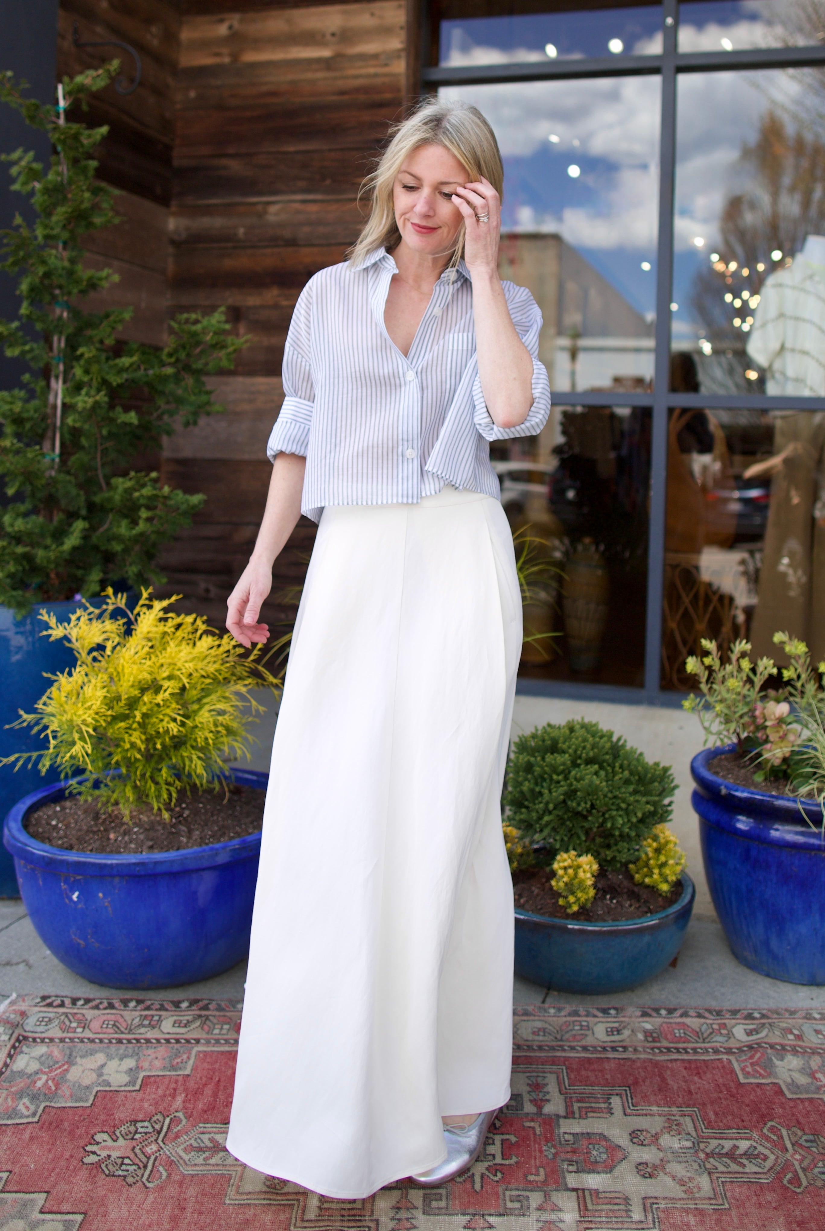 Image of mature woman wearing luxury brand TWP Cecelias coated linen pleated skirt with hidden seam pockets in elegant bone white