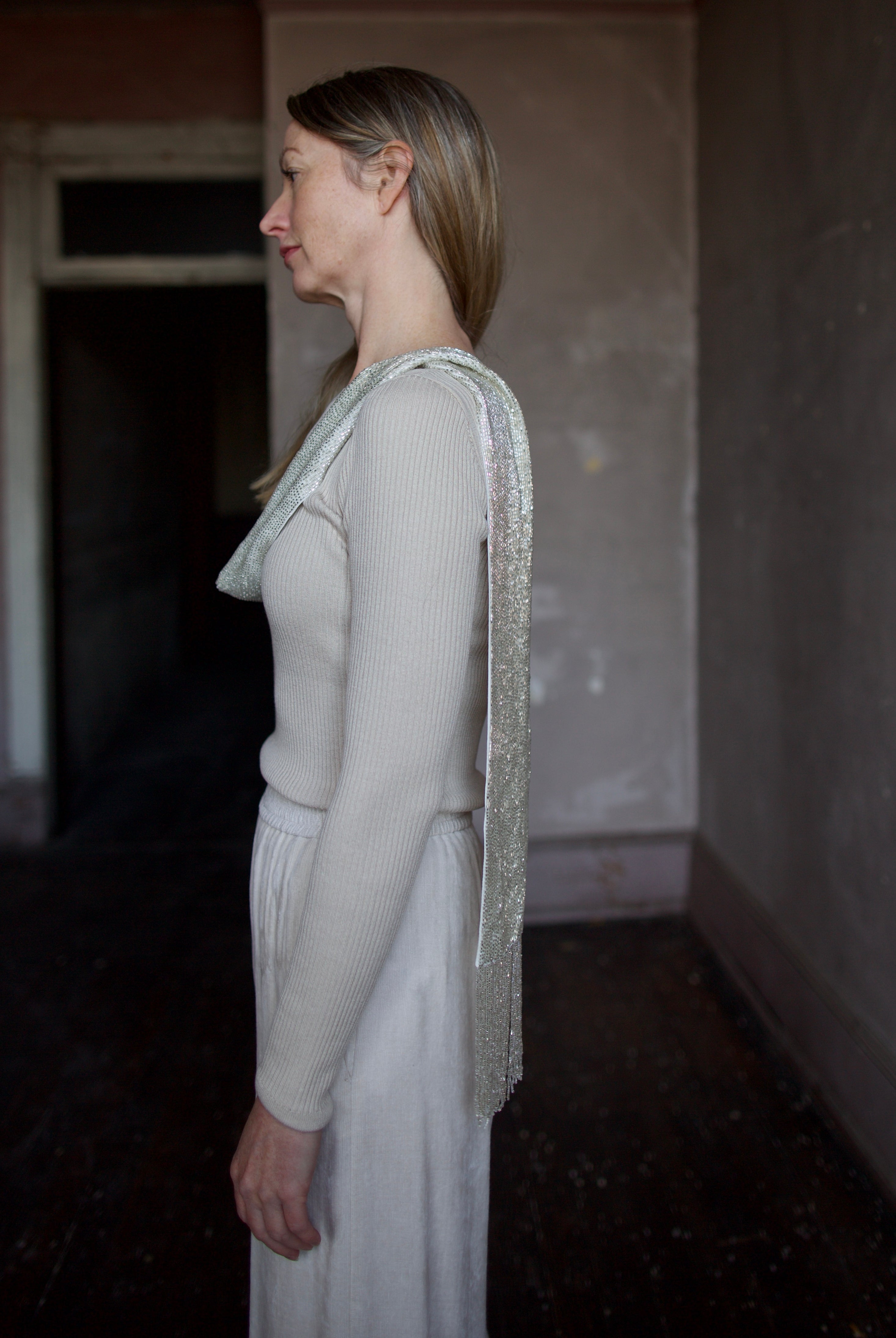 image of the side of a woman wearing the TWP ribbed top and beaded scarf