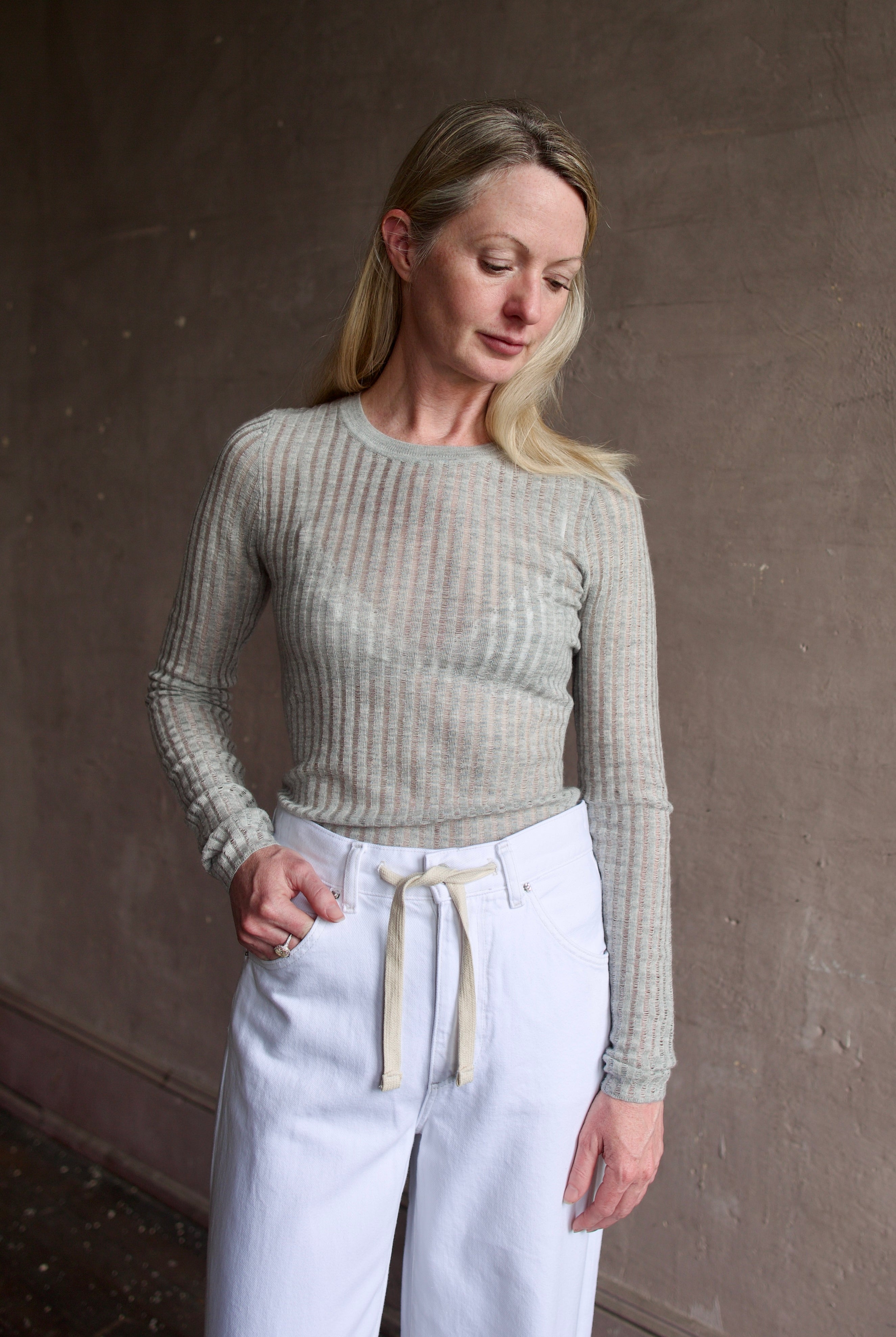 Mature woman wearing luxury brand TWP grey fine cashmere pointelle knit crewneck top perfect lightweight layering in cool weather