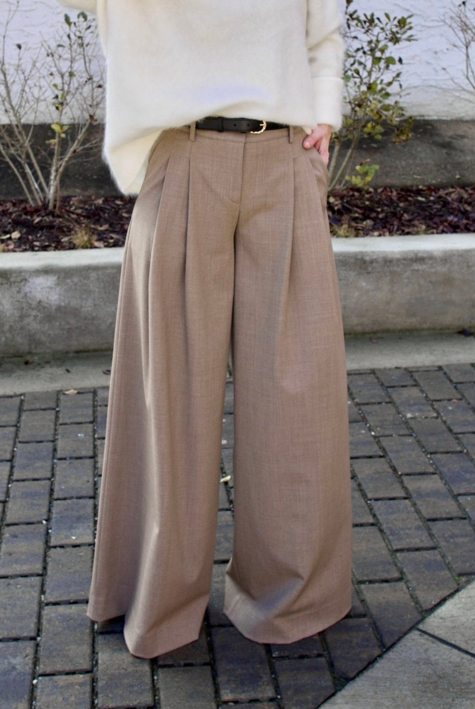 Image of a woman wearing the TWP new didi pants in sandstone, the Ulla Johnson gia belt, and the Lisa Yang Margareta sweater.