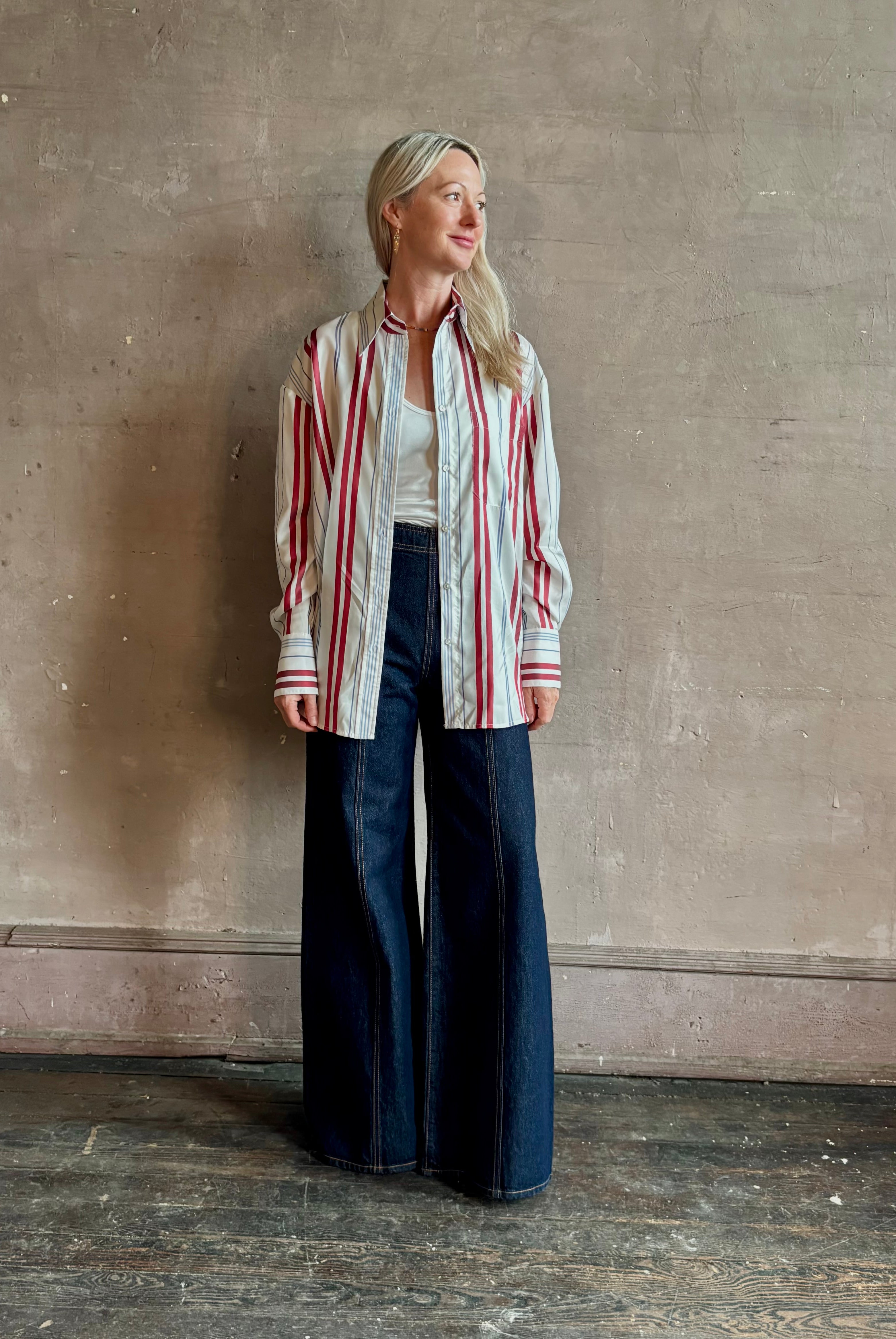 Mature woman wearing Big Joe Shirt from TWP rendered in an ivory, blue, and wine striped colorway and crafted from silk in the USA with collar, button front and wide cuffed long sleeves in a generous oversized fit