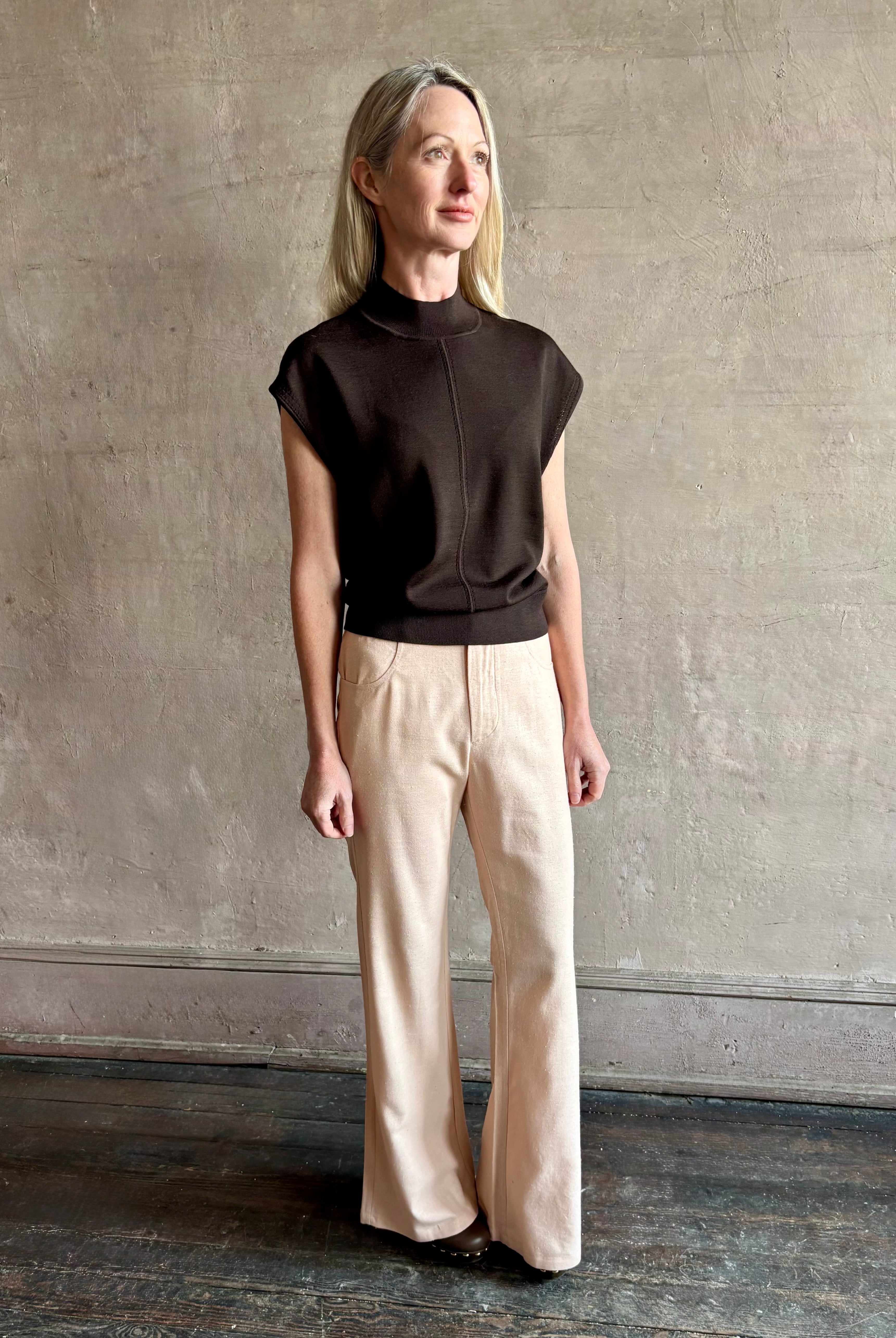 Woman wearing TWP Chocolate brown Wren Sweater in Premium Merino Wool Knitwear with mock neck and cap sleeve