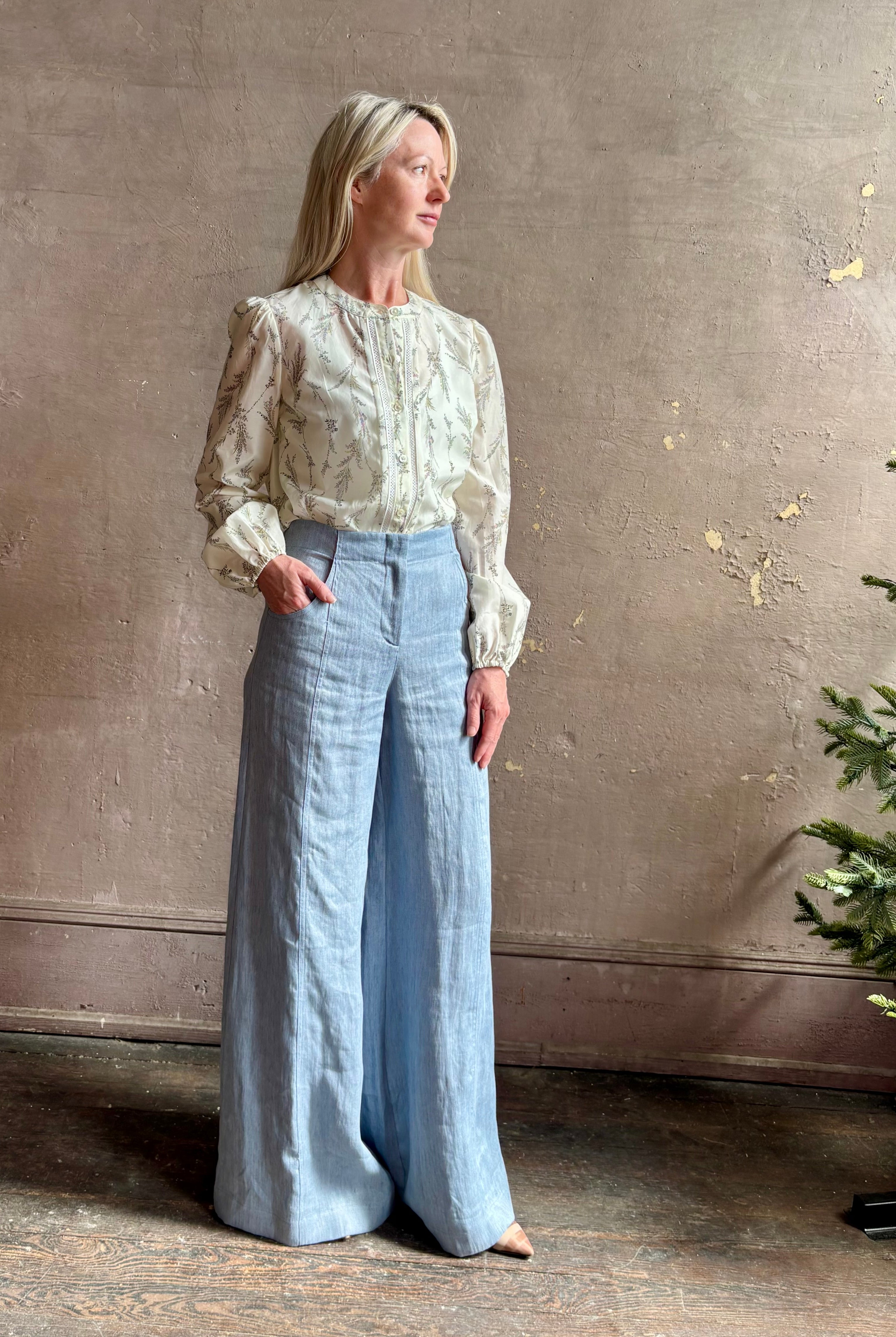 Mature woman wearing luxury brand TWP Demie High Rise wide leg indigo hemp Pants offers timeless refinement and expert craftsmanship