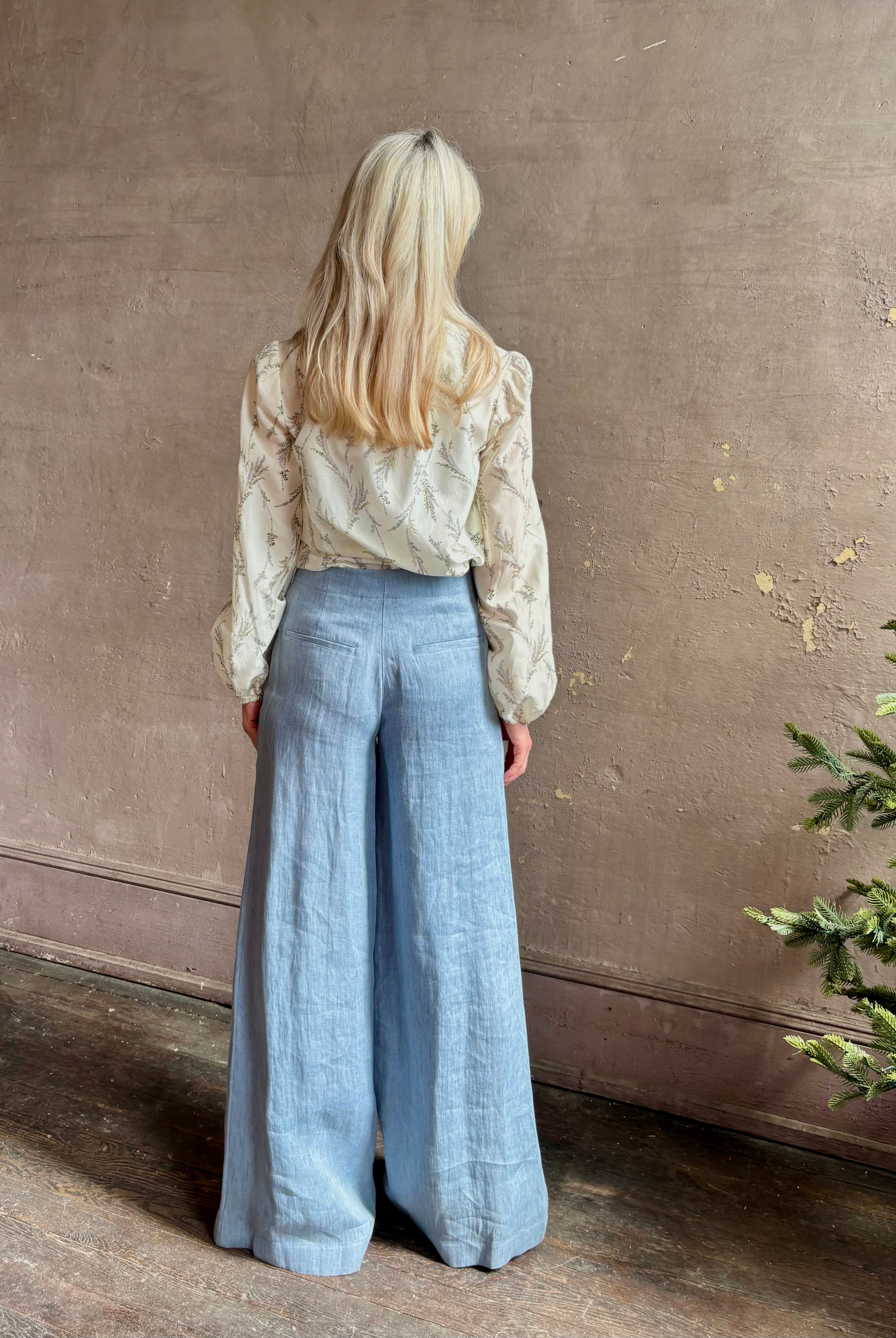 Mature woman wearing luxury brand TWP Demie High Rise wide leg indigo hemp Pants offers timeless refinement and expert craftsmanship