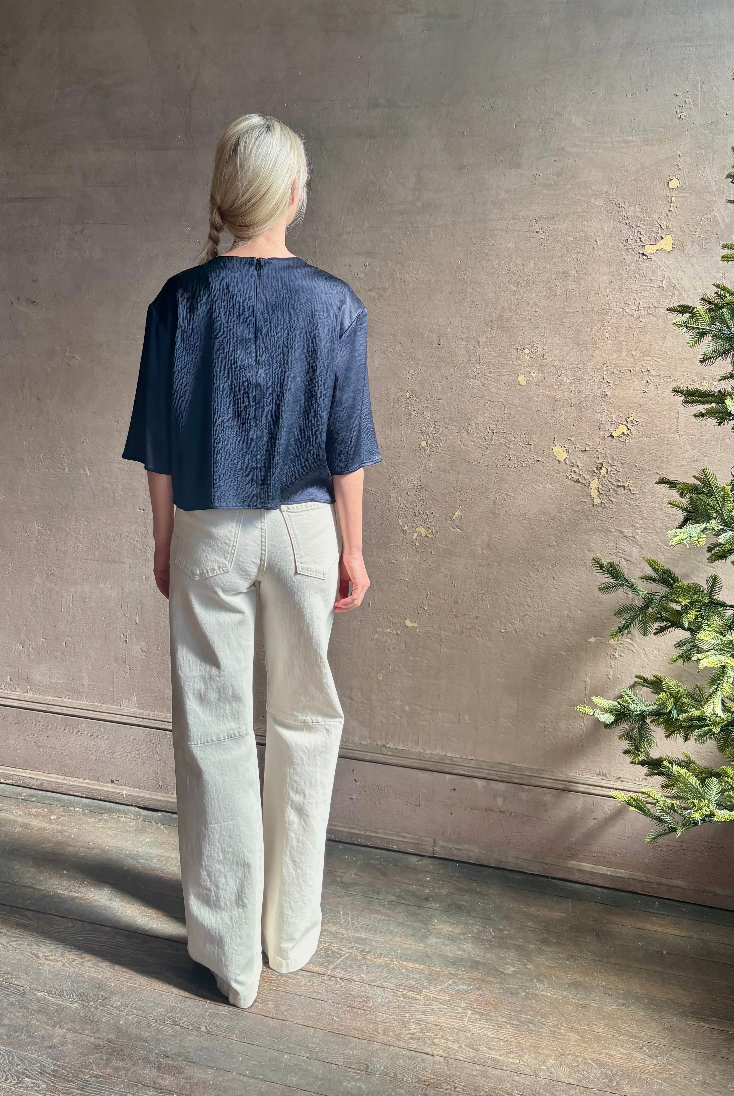 Mature woman wearing Women's luxury clothing brand TWP Ex T in premium hammered satin with short sleeves crew neck and a casual front pocket rendered in a beautiful navy blue hue