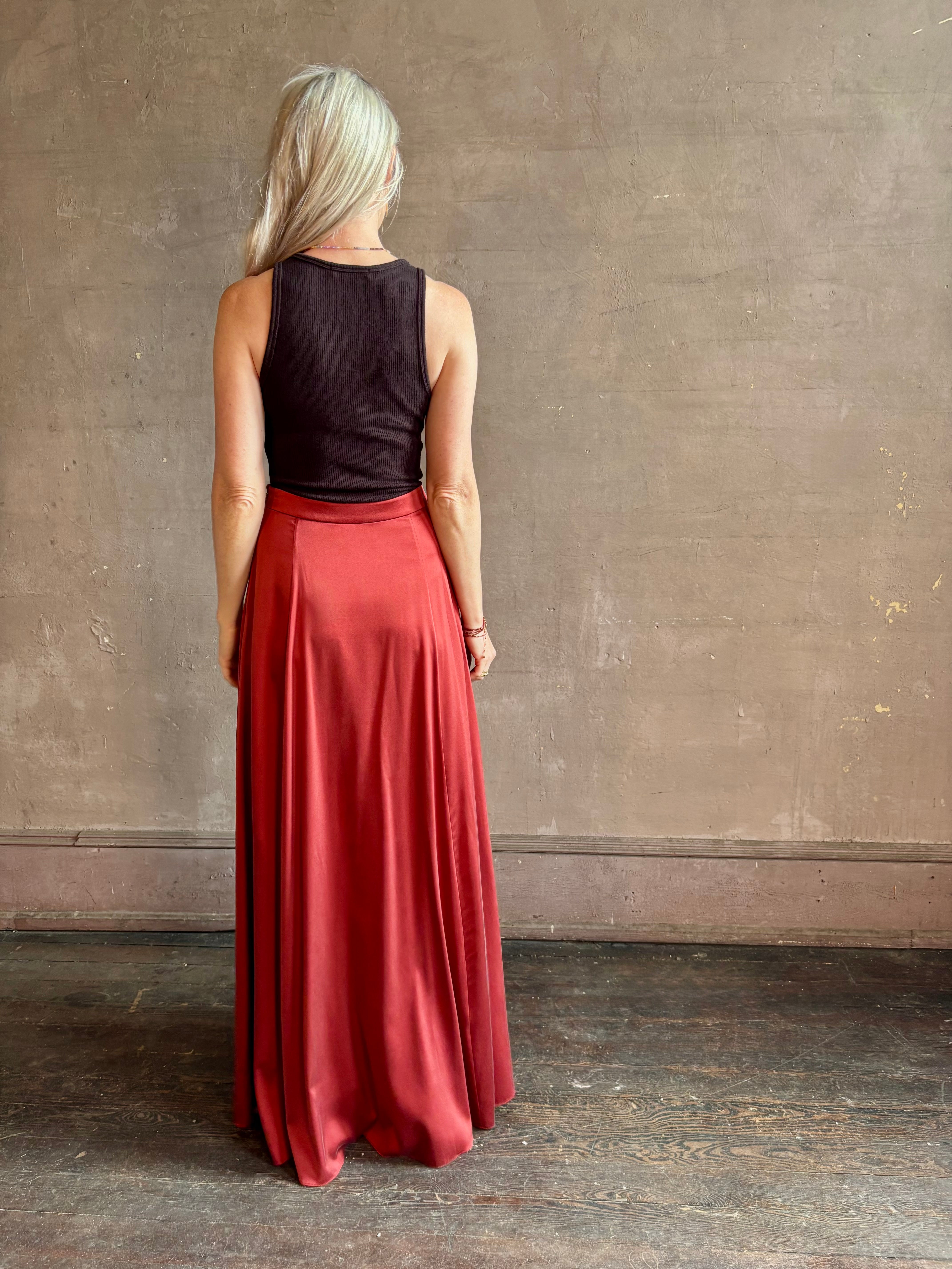 Mature woman wearing Flowy Maxi A-Line Skirt from TWP rendered in a rich red currant and crafted from a luxurious silk blend with hidden seam zip closure and tailored waistband