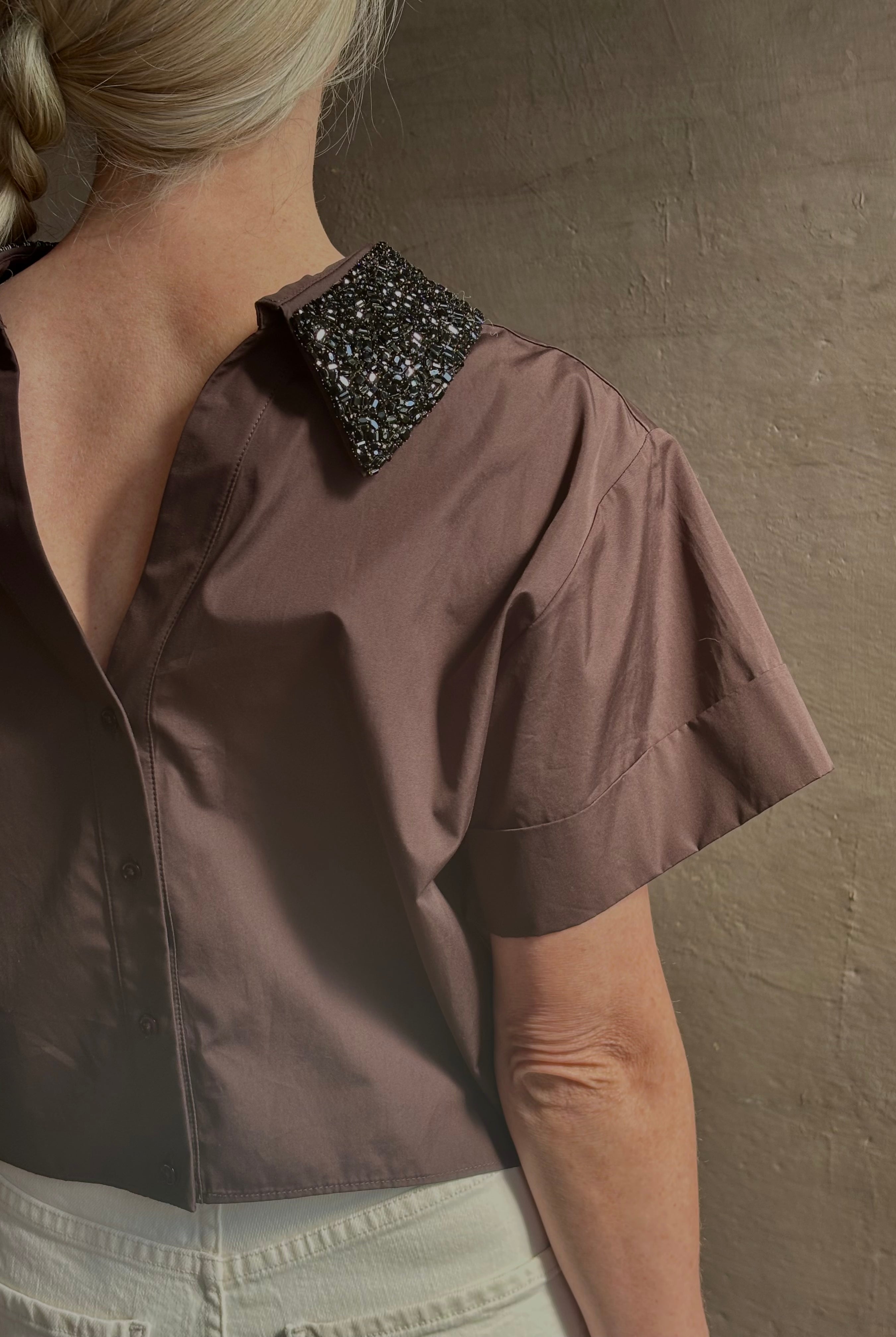Mature woman wearing Forever and Always with Crystal Collar Top from TWP women's luxury designer blouse rendered in chocolate brown and crafted from 100% cotton in the USA with crystal collar, short sleeves and reversible