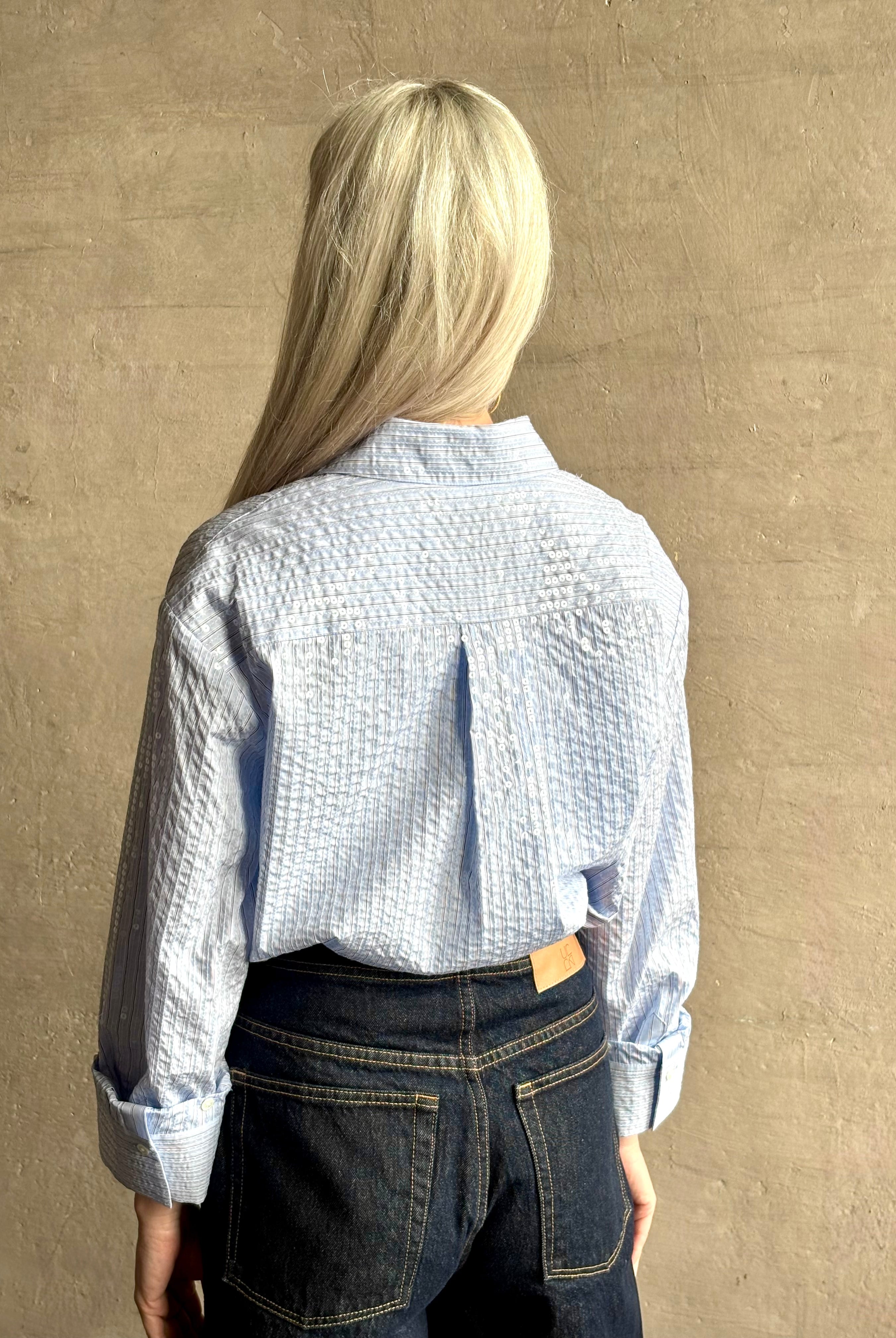 Mature woman wearing JD blue and white stripe collared button-down shirt by TWP with sequin embellishments
