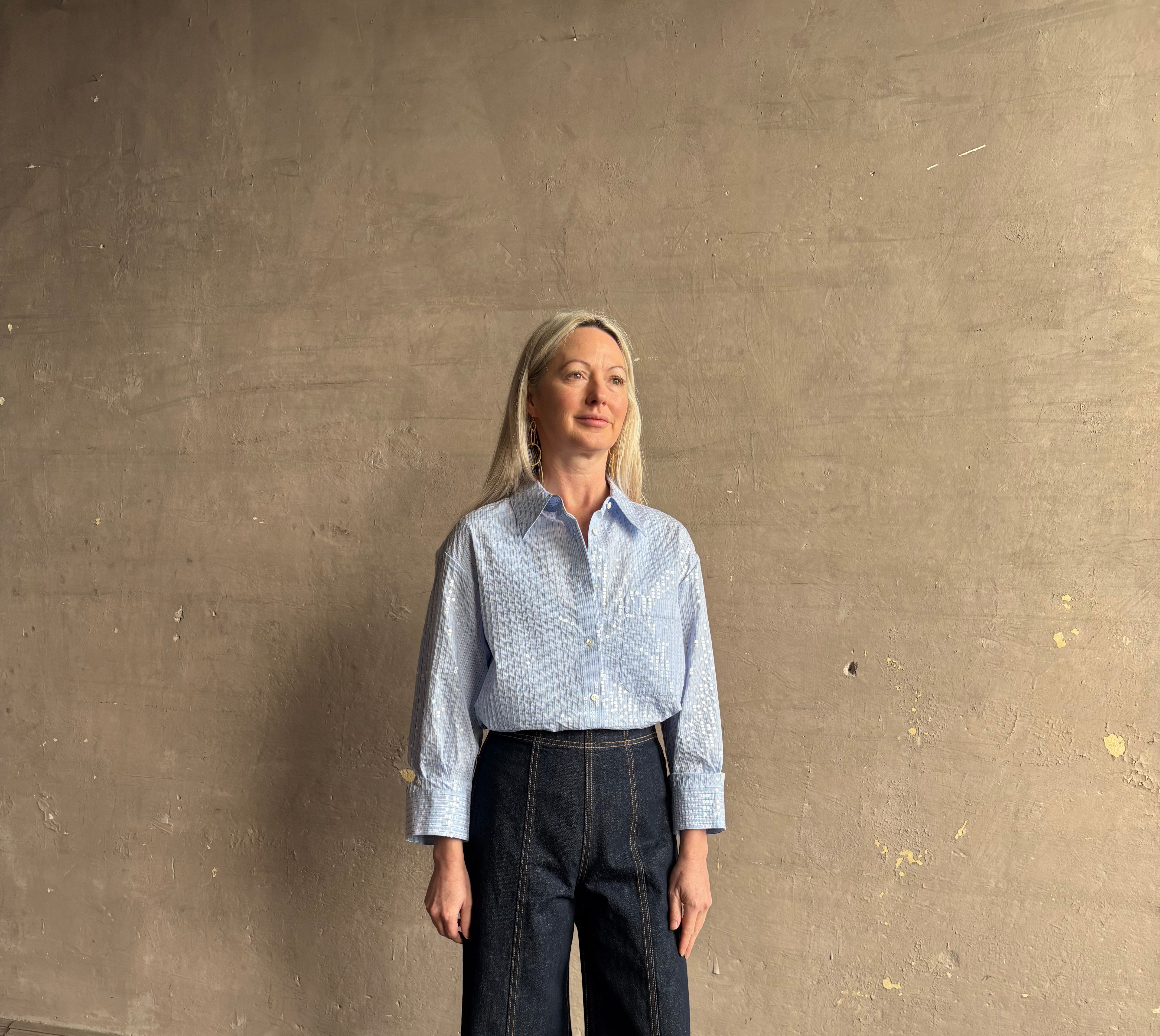 Mature woman wearing JD blue and white stripe collared button-down shirt by TWP with sequin embellishments