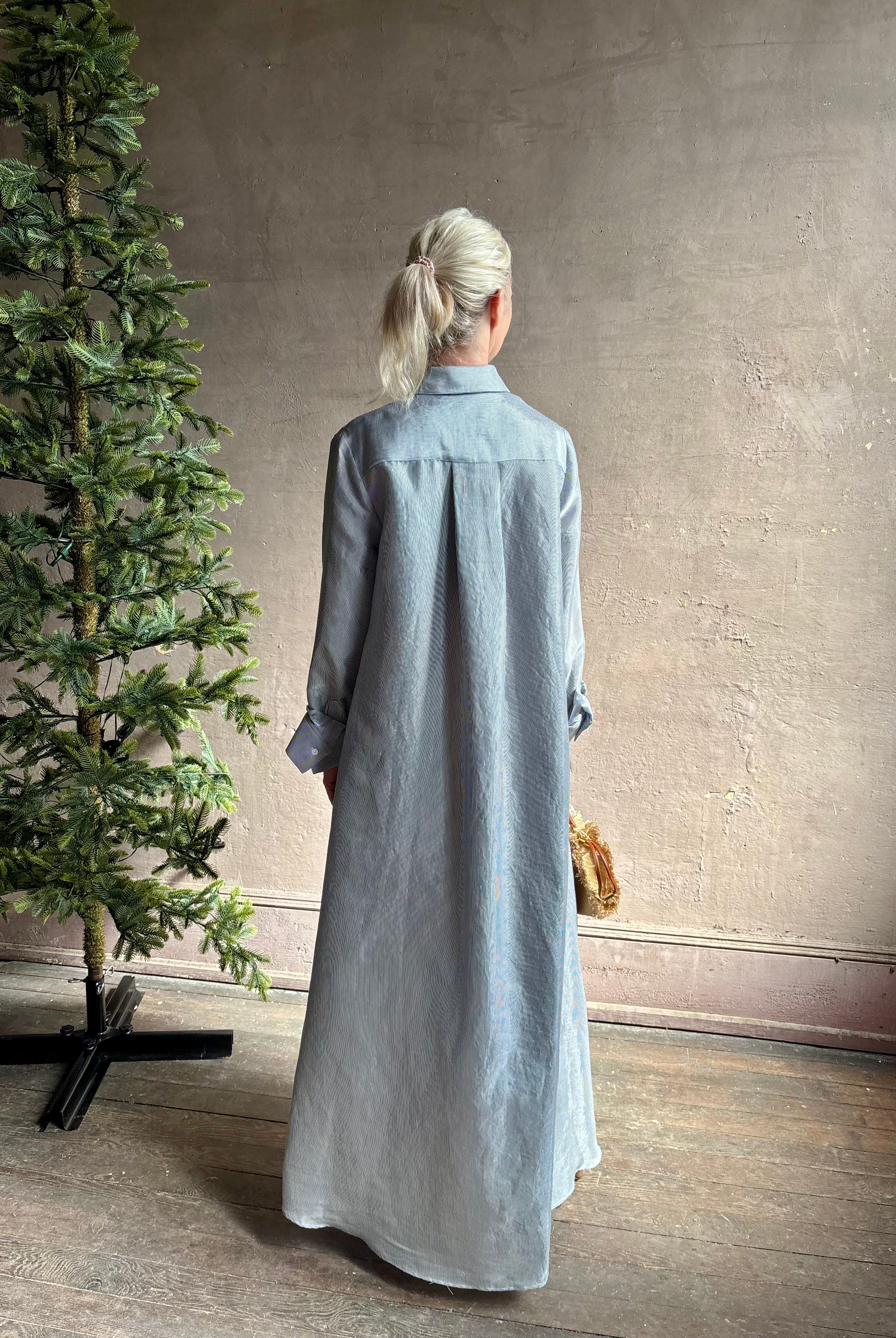 Mature woman wearing luxury Jenny's Gown from designer TWP rendered in a lumines white and blue stripe print and crafted in USA from a viscose and lorex blend this lightweight long sleeve maxi dress drapes beautifully with a flowing quality that moves with understated grace