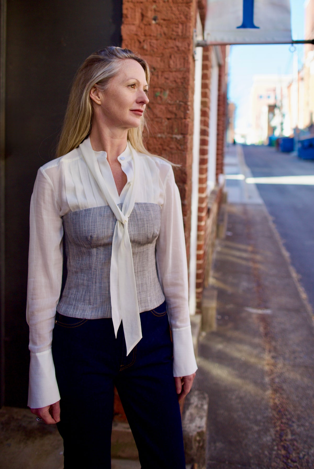 Mature woman wearing luxury brand TWP Jillian cotton-wool bustier in heather grey with bust darts zip closure layered over blouse