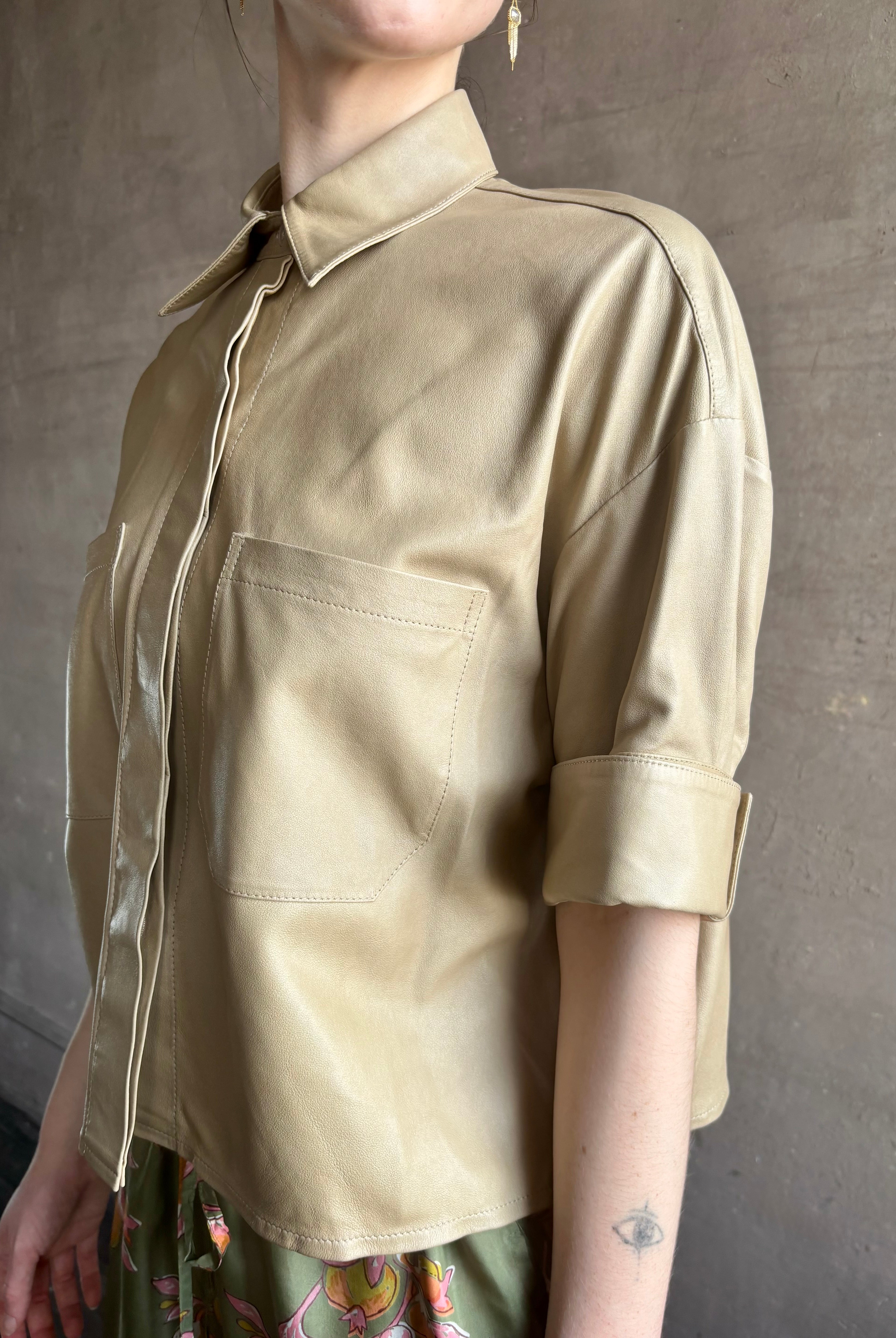 Woman wearing luxury designer TWP premium Lambskin Leather button up collared shirt with cuffed short sleeves in a neutral khaki that can double as a lightweight jacket