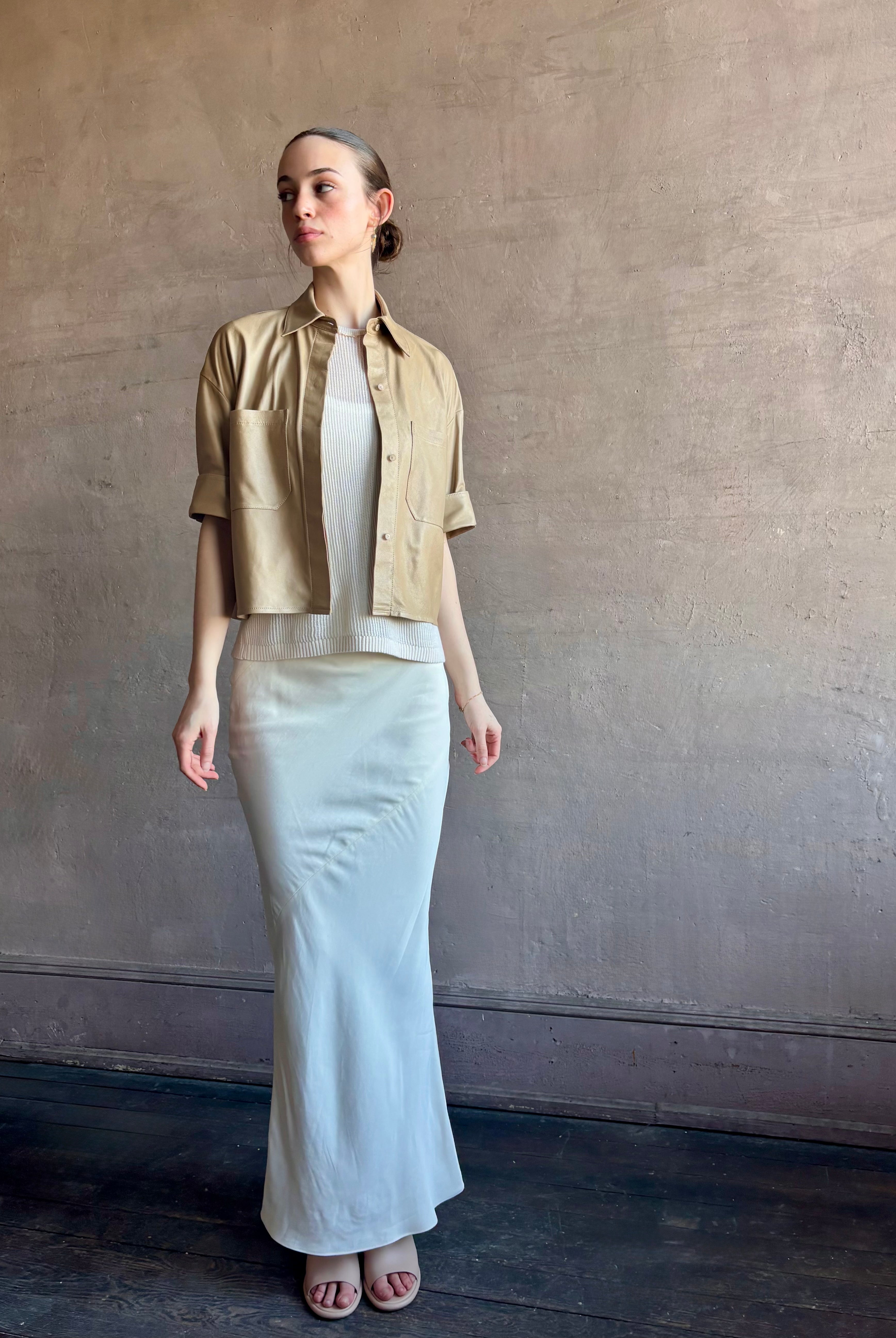 Woman wearing luxury designer TWP premium Lambskin Leather button up collared shirt with cuffed short sleeves in a neutral khaki that can double as a lightweight jacket