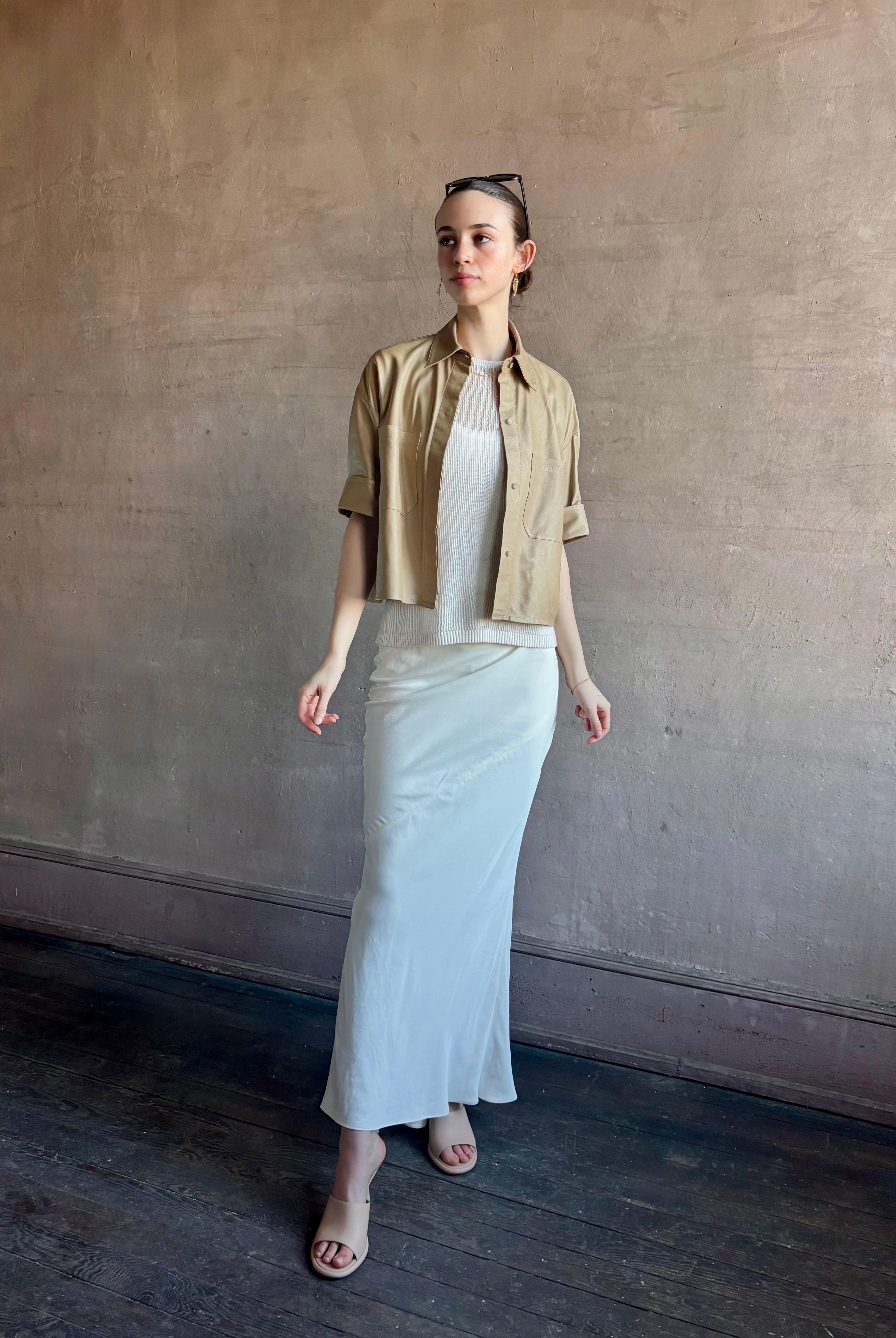 Woman wearing luxury designer TWP premium Lambskin Leather button up collared shirt with cuffed short sleeves in a neutral khaki that can double as a lightweight jacket