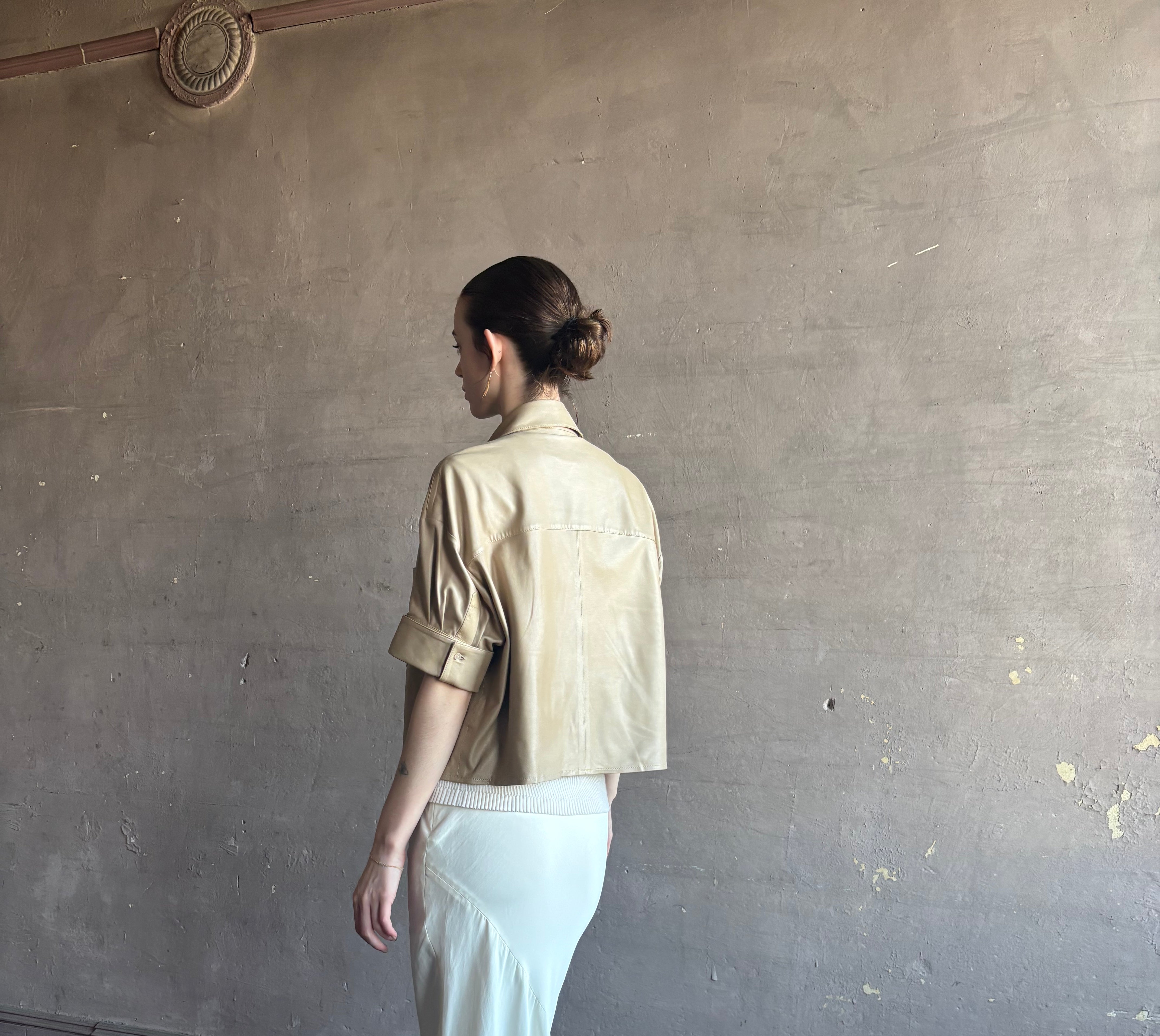 Woman wearing luxury designer TWP premium Lambskin Leather button up collared shirt with cuffed short sleeves in a neutral khaki that can double as a lightweight jacket