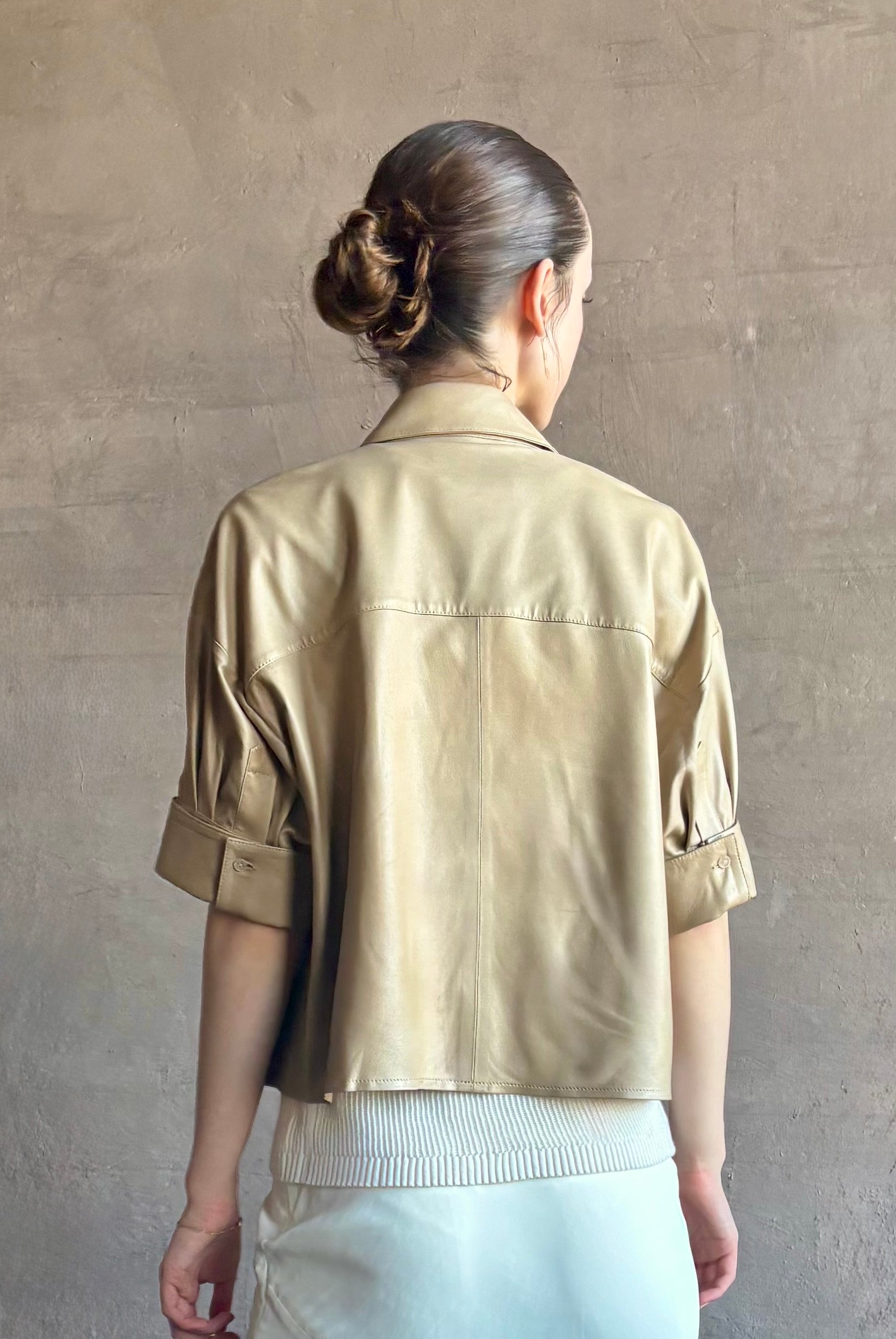 Woman wearing luxury designer TWP premium Lambskin Leather button up collared shirt with cuffed short sleeves in a neutral khaki that can double as a lightweight jacket