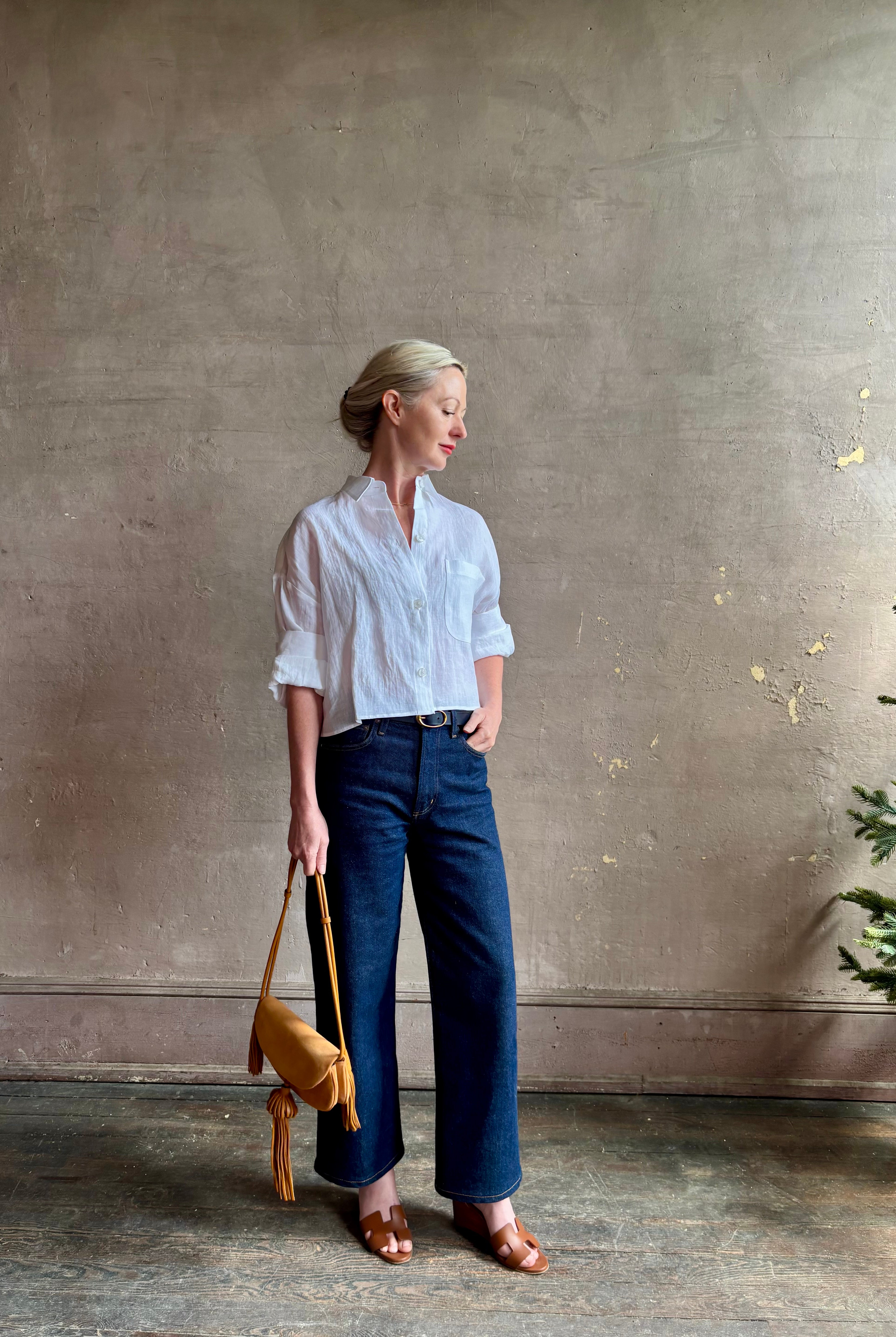 Mature woman wearing the Next Ex Top from TWP rendered in a crisp white and crafted from premium linen in New York City, this luxury linen top offers effortless cool girl with an intentionally oversized boxy silhouette with tailored half sleeve cuffs, collared button - down menswear inspired with a single front pocket