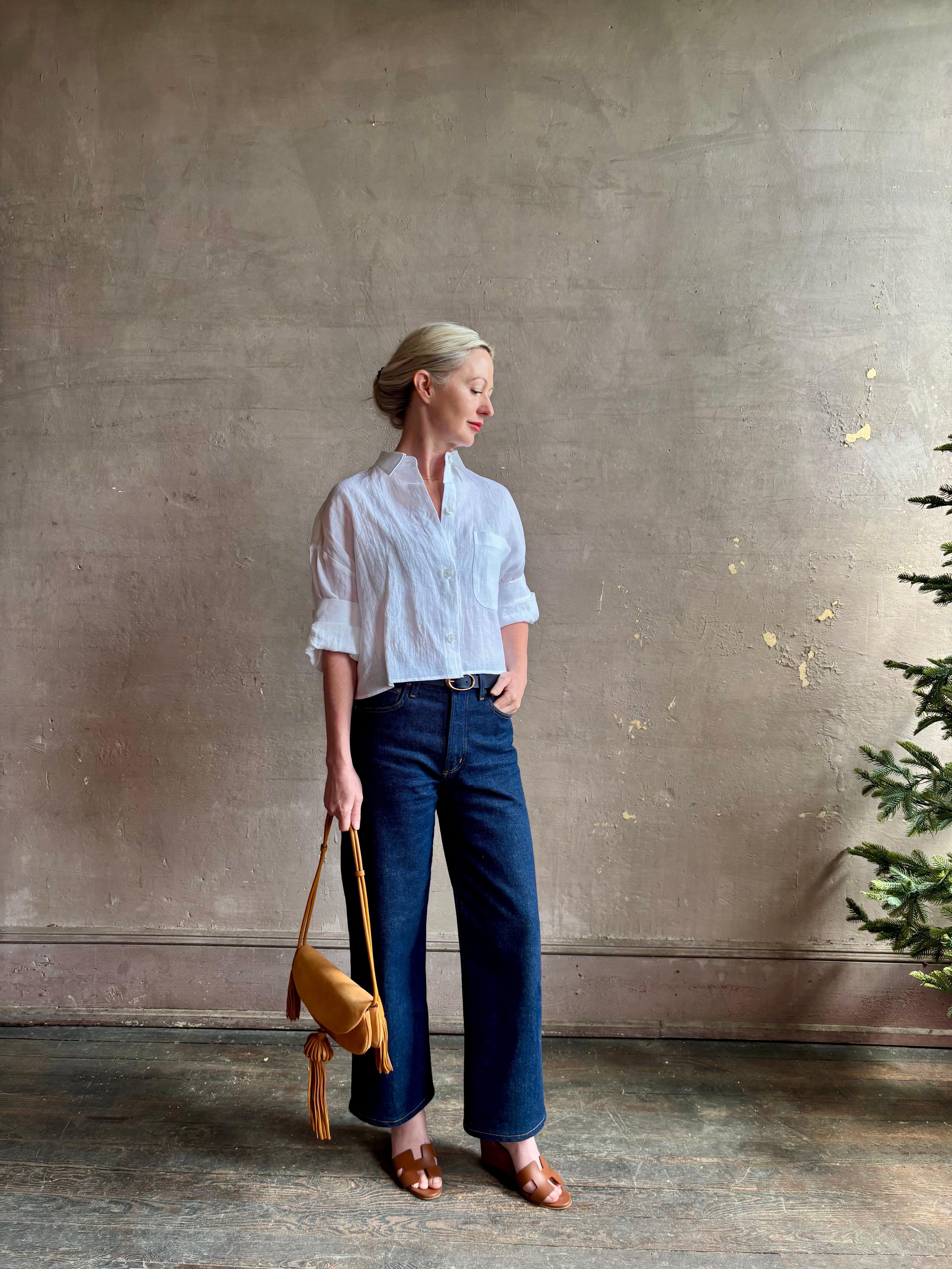 Mature woman wearing the Next Ex Top from TWP rendered in a crisp white and crafted from premium linen in New York City, this luxury linen top offers effortless cool girl with an intentionally oversized boxy silhouette with tailored half sleeve cuffs, collared button - down menswear inspired with a single front pocket