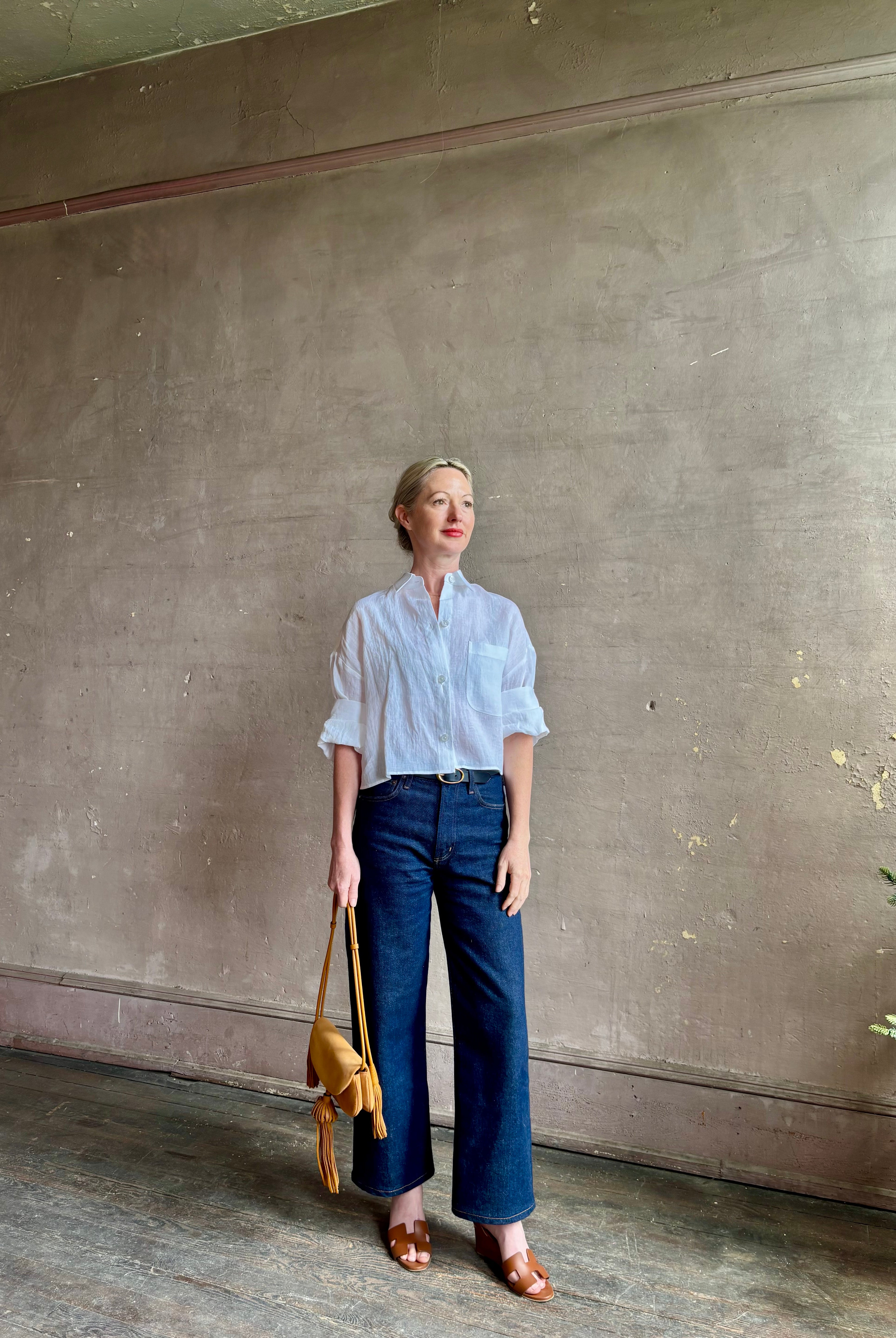 Mature woman wearing the Next Ex Top from TWP rendered in a crisp white and crafted from premium linen in New York City, this luxury linen top offers effortless cool girl with an intentionally oversized boxy silhouette with tailored half sleeve cuffs, collared button - down menswear inspired with a single front pocket