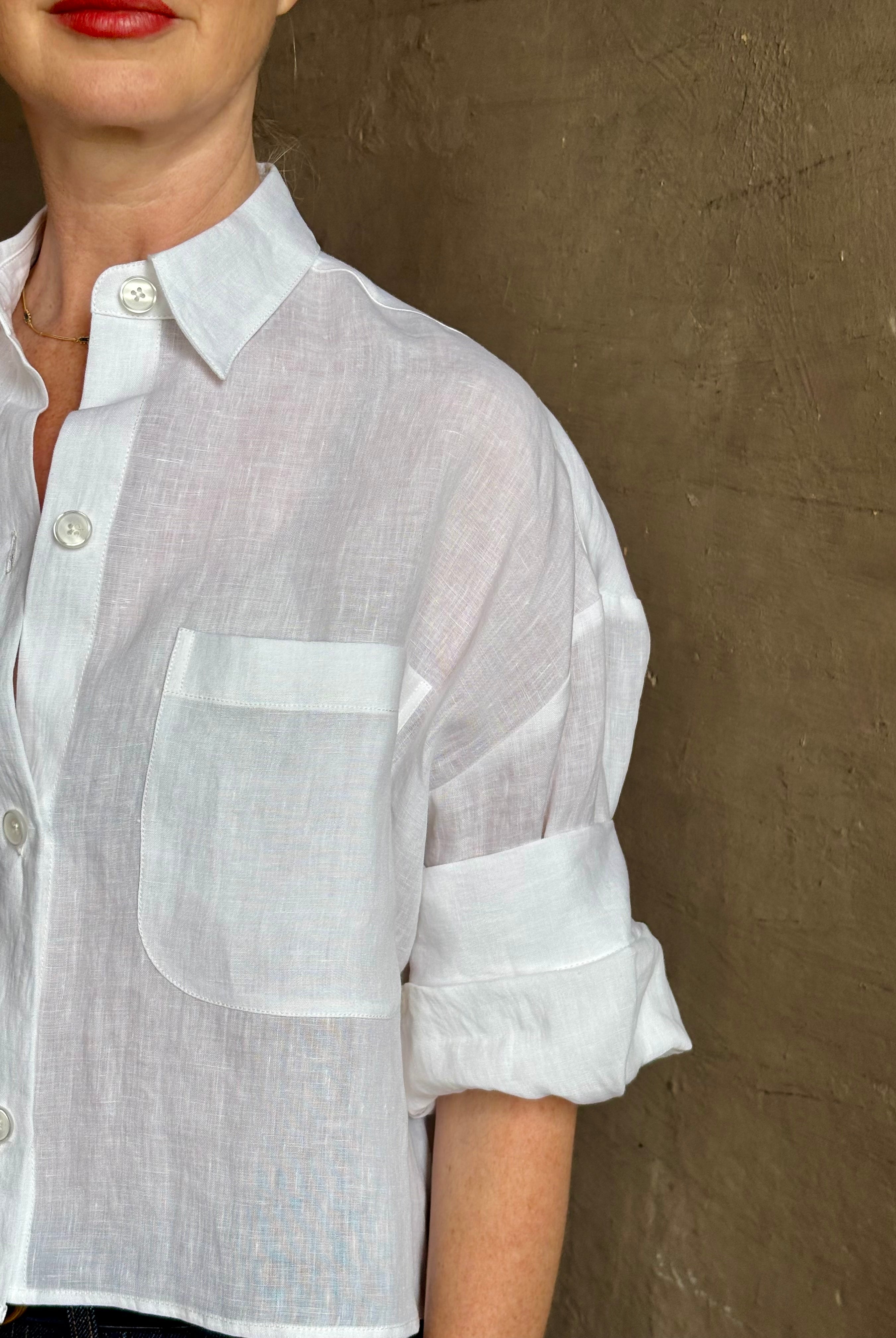 Mature woman wearing the Next Ex Top from TWP rendered in a crisp white and crafted from premium linen in New York City, this luxury linen top offers effortless cool girl with an intentionally oversized boxy silhouette with tailored half sleeve cuffs, collared button - down menswear inspired with a single front pocket