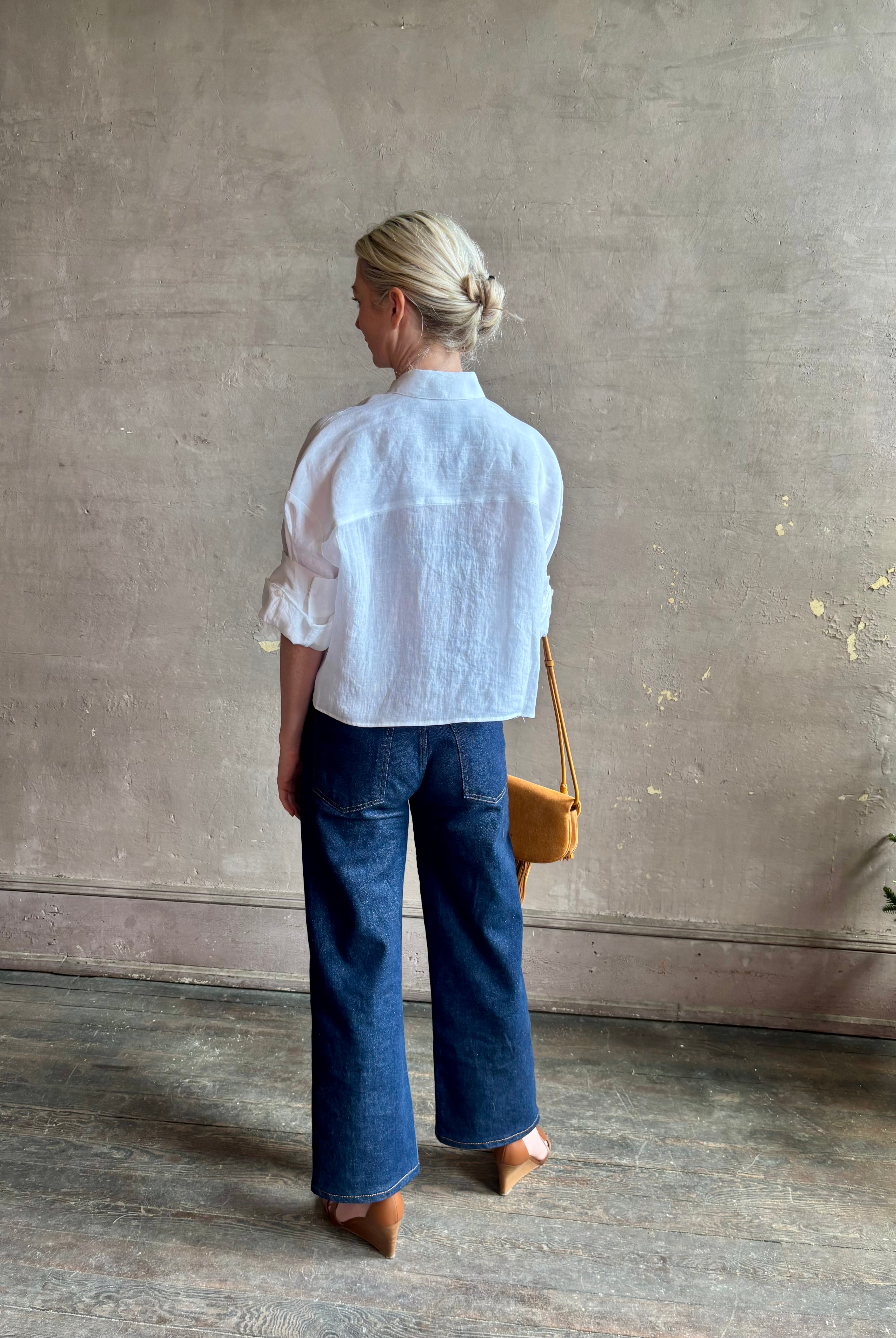 Mature woman wearing the Next Ex Top from TWP rendered in a crisp white and crafted from premium linen in New York City, this luxury linen top offers effortless cool girl with an intentionally oversized boxy silhouette with tailored half sleeve cuffs, collared button - down menswear inspired with a single front pocket
