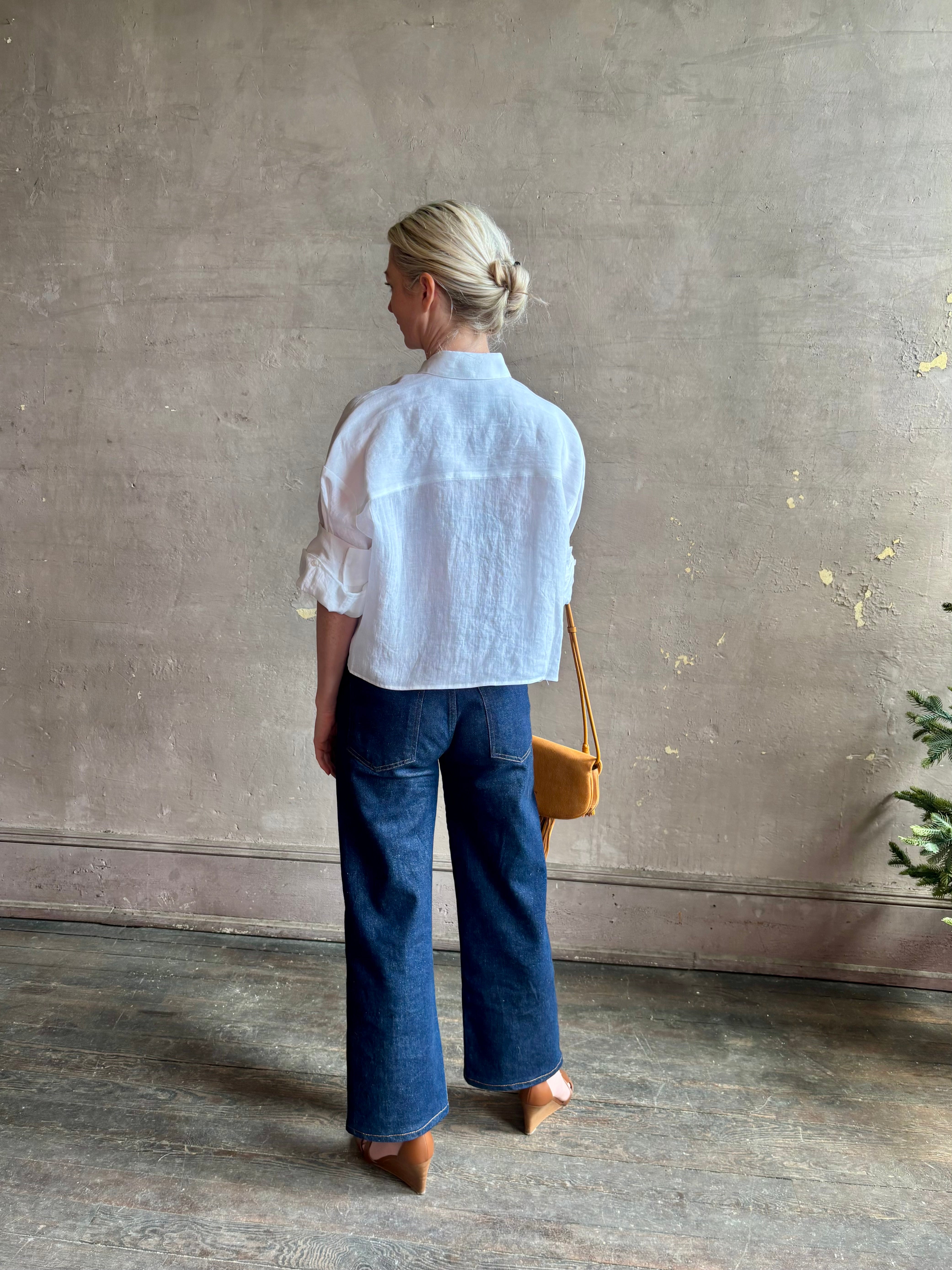 Mature woman wearing the Next Ex Top from TWP rendered in a crisp white and crafted from premium linen in New York City, this luxury linen top offers effortless cool girl with an intentionally oversized boxy silhouette with tailored half sleeve cuffs, collared button - down menswear inspired with a single front pocket