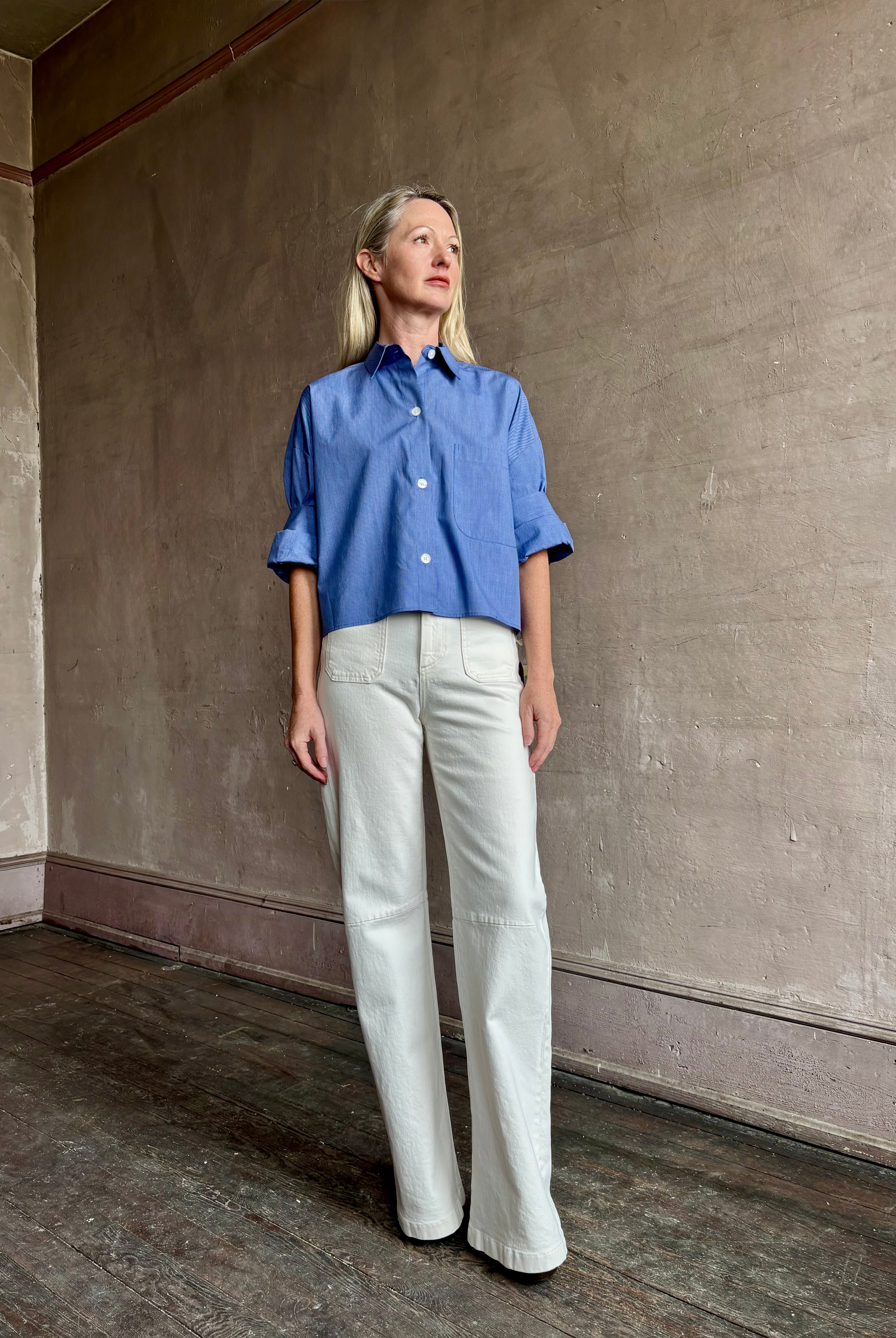 Image of mature model wearing classic cotton poplin button down next ex top by luxury brand TWP in a blue and white stripe.