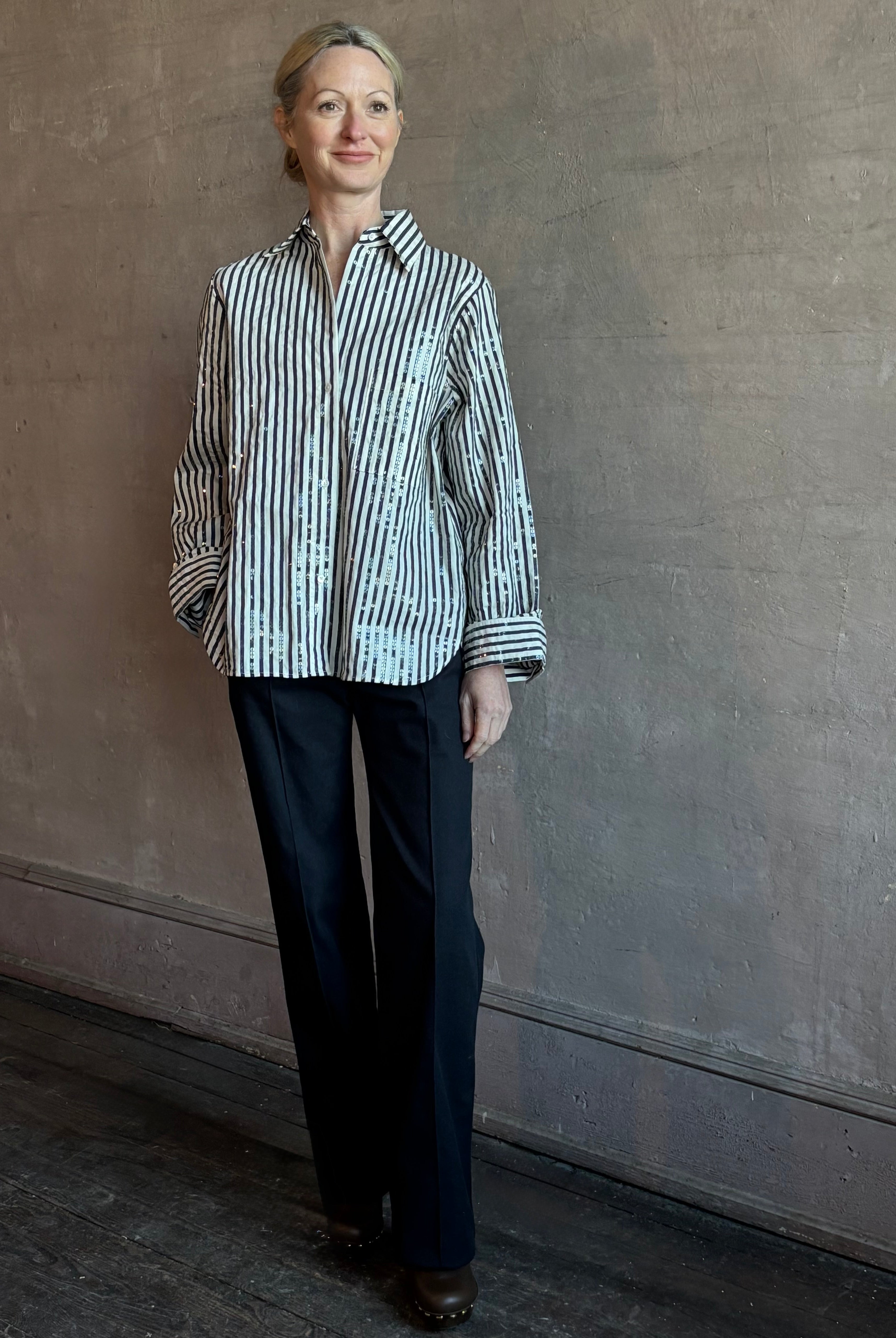 Mature woman wearing TWP premium cotton-blend button down indigo striped shirt with sequins, long sleeve and collar