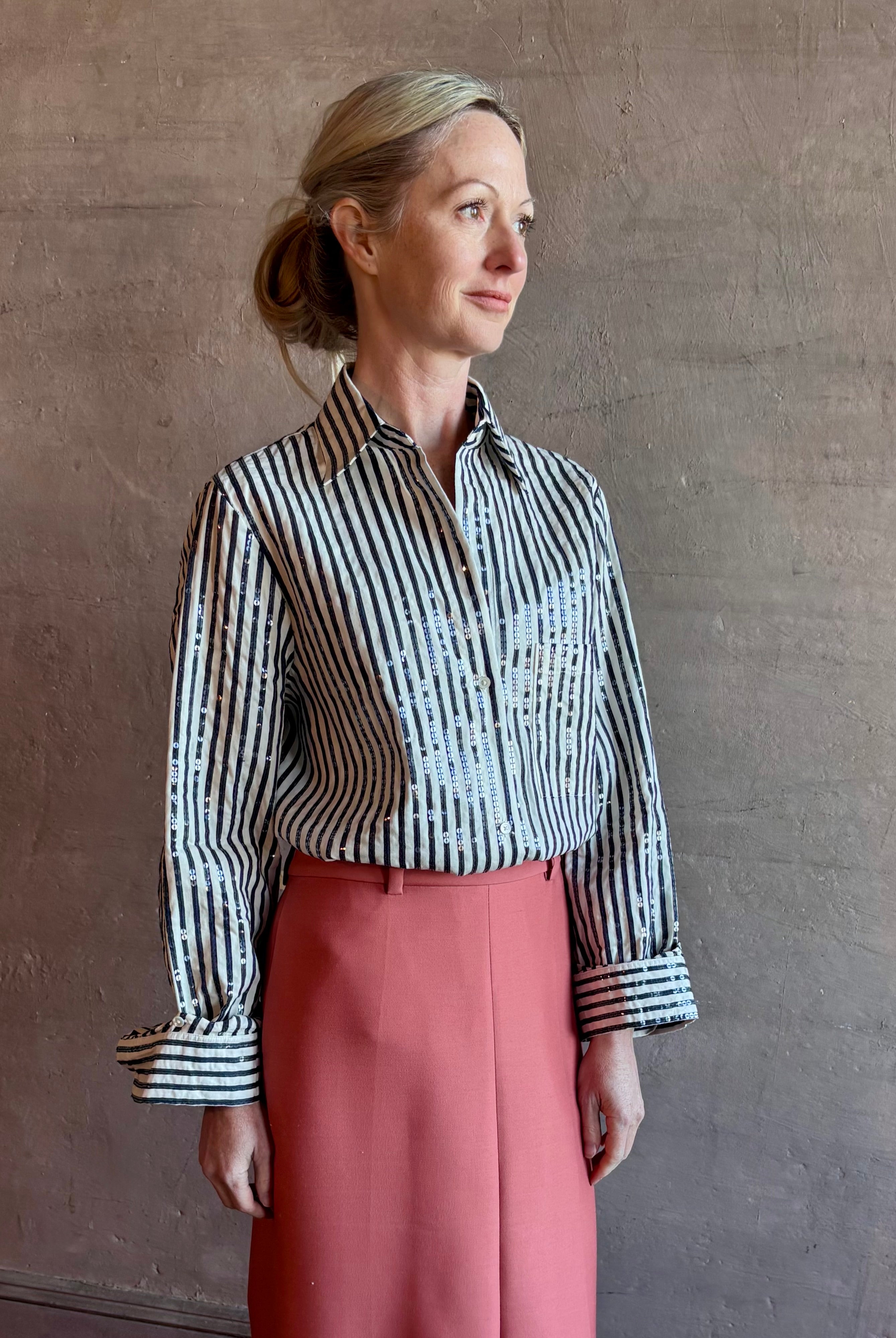 Mature woman wearing TWP premium cotton-blend button down indigo striped shirt with sequins, long sleeve and collar
