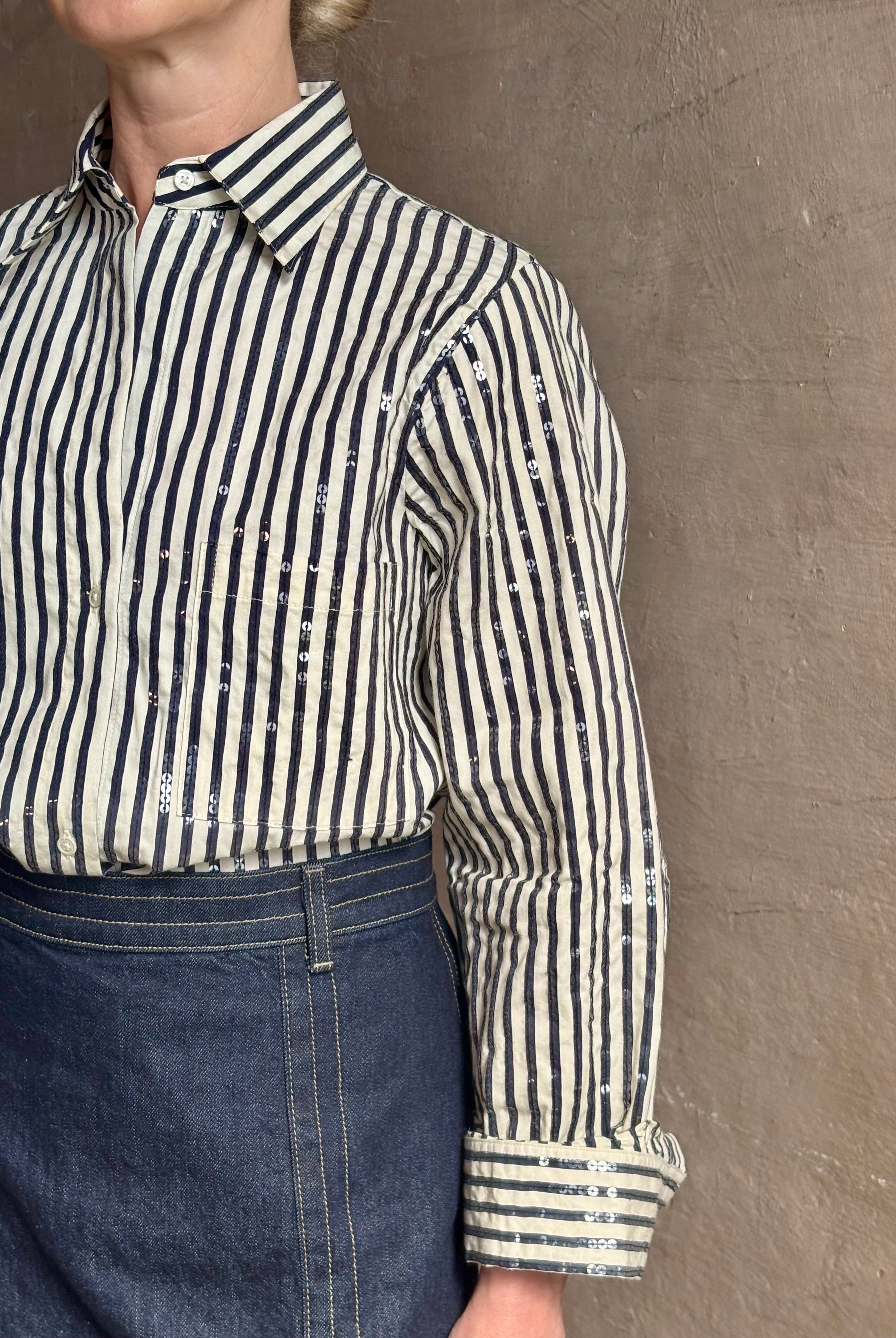 Mature woman wearing TWP premium cotton-blend button down indigo striped shirt with sequins, long sleeve and collar