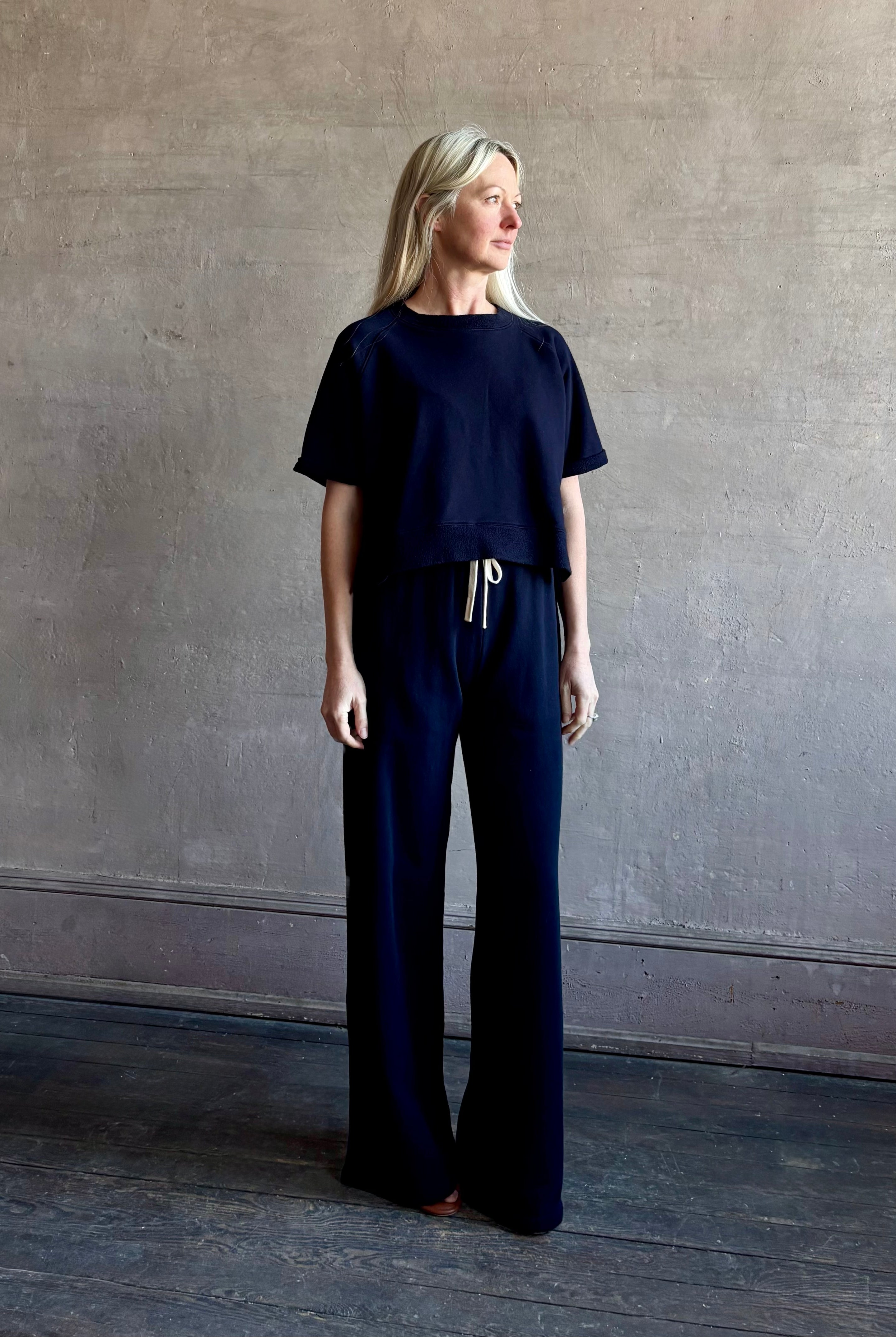 Mature woman wearing the PJ Pant from TWP is a luxuriously relaxed women's designer lounge pant crafted from cotton with a straight leg and effortless pull-on waist