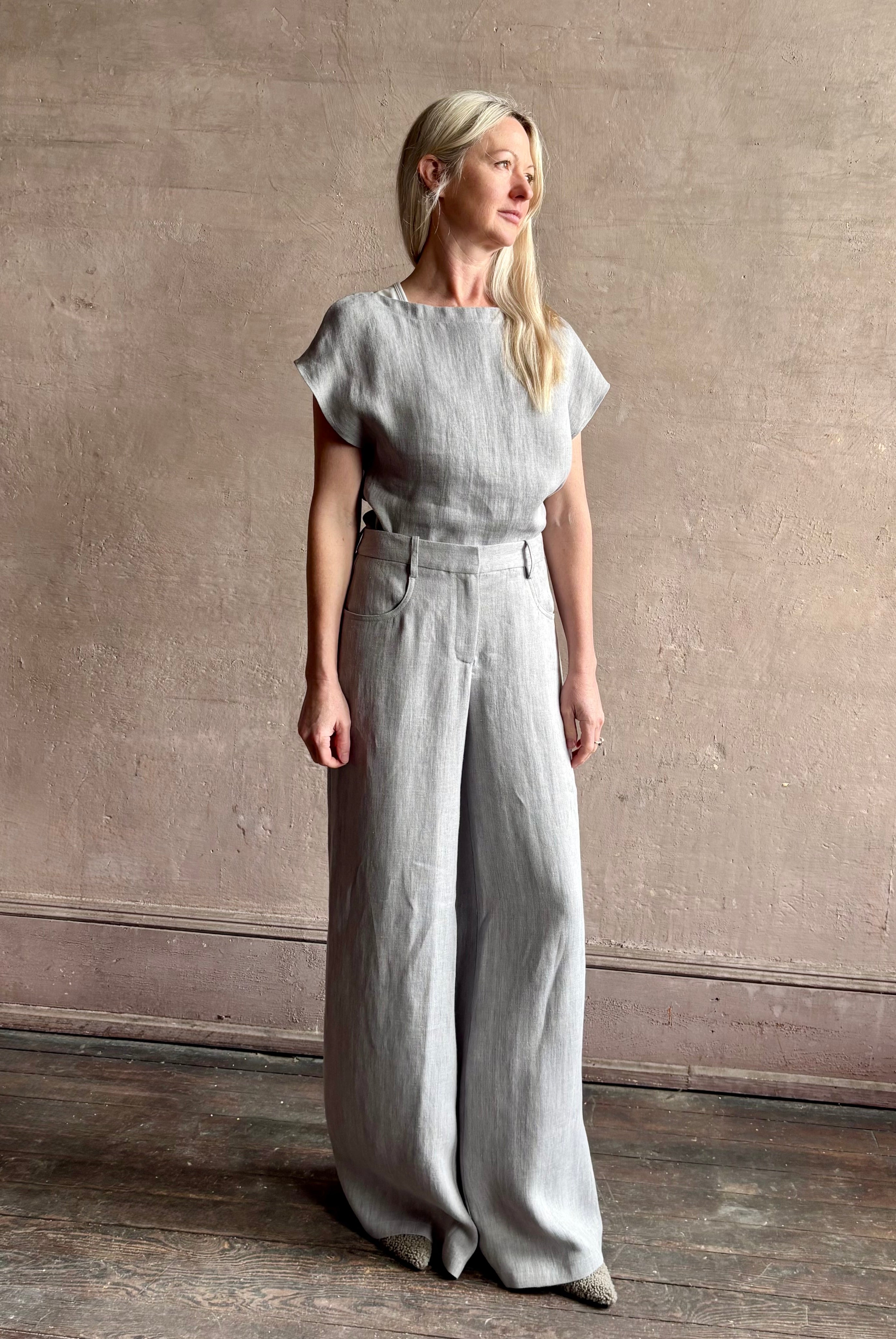 Mature woman wearing the Simple T Top from TWP that is rendered in a light heather grey hemp with short sleeves and boat neckline