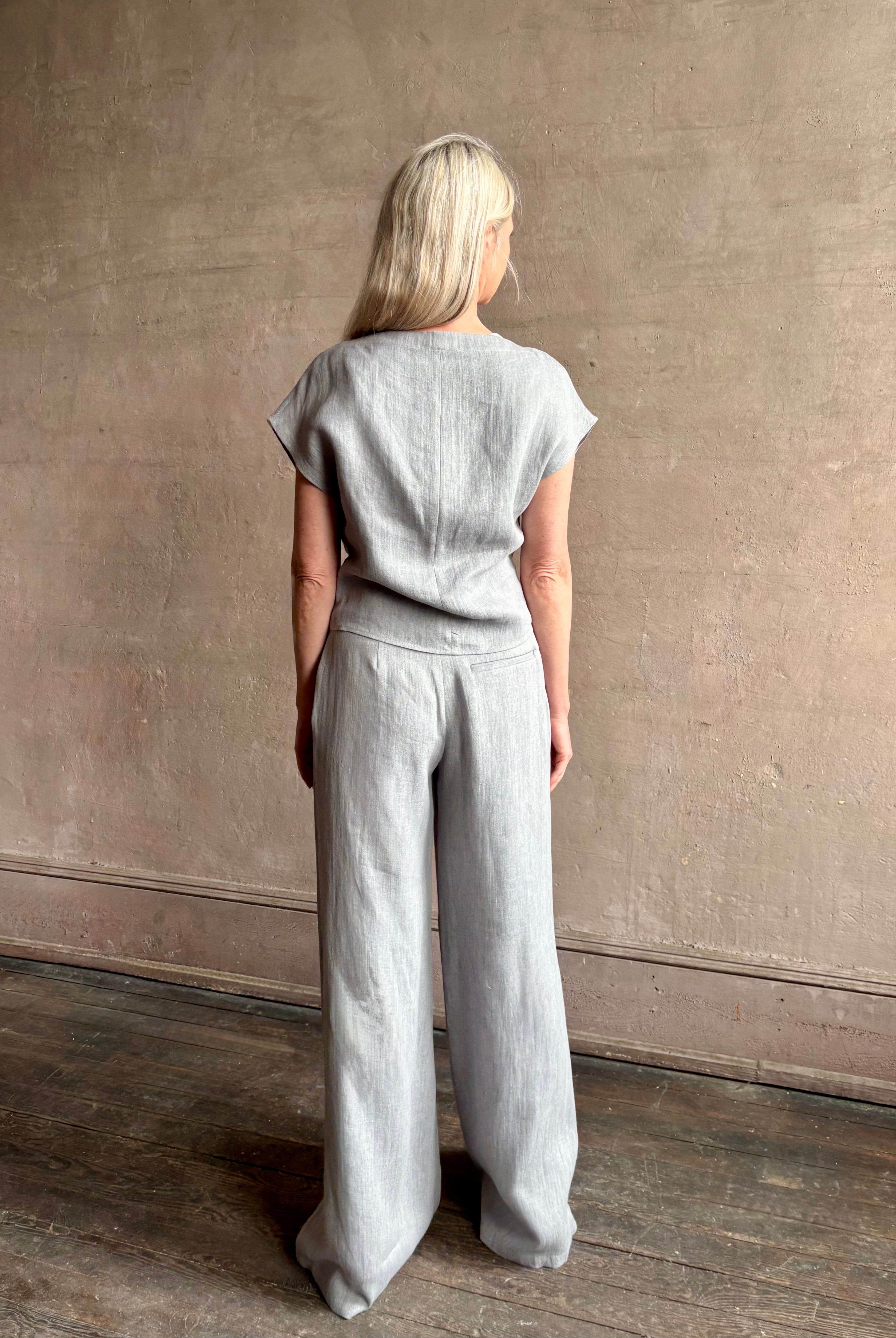 Mature woman wearing the Simple T Top from TWP that is rendered in a light heather grey hemp with short sleeves and boat neckline