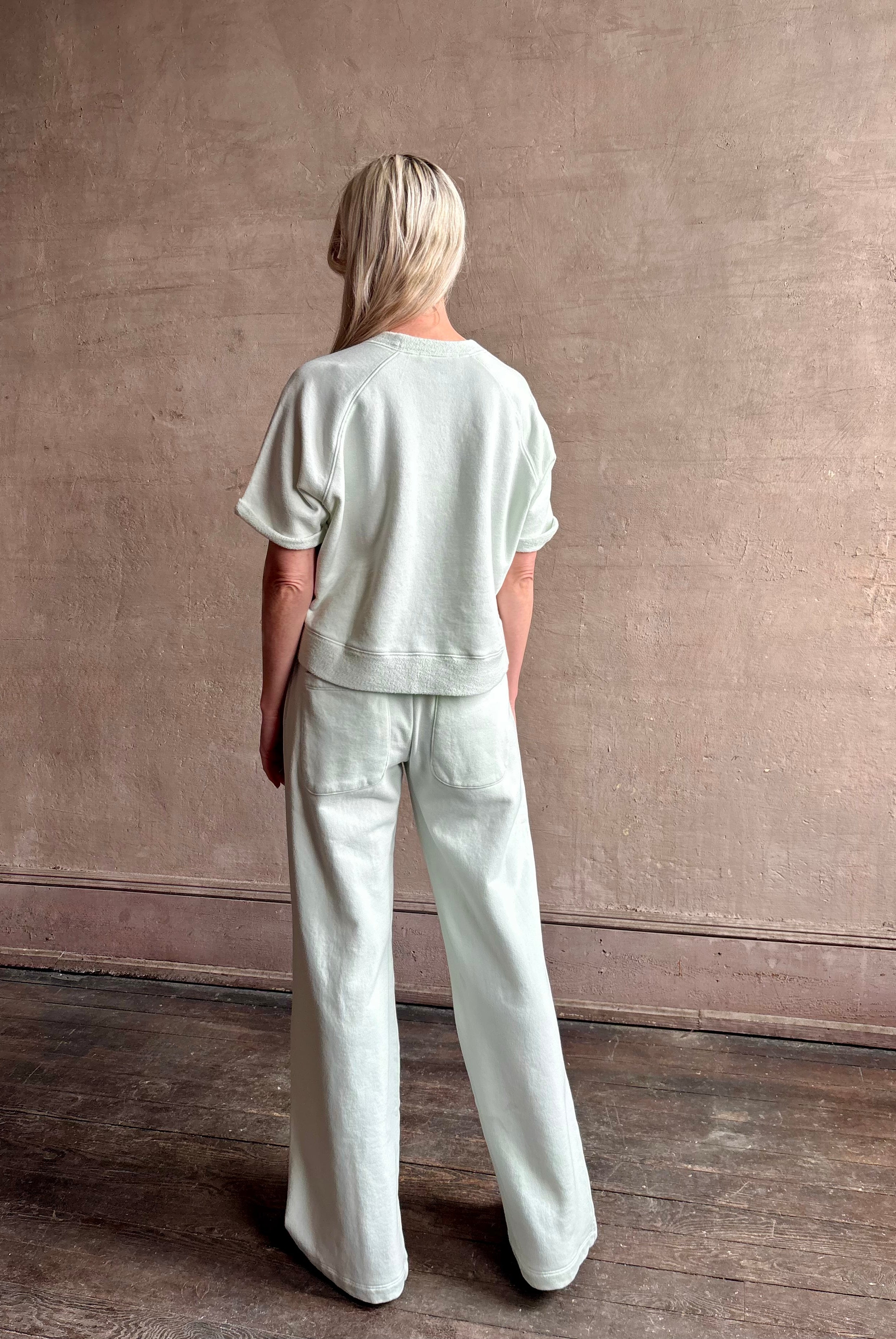 Mature woman wearing Slouchy Rolled Tee Top from TWP rendered in a sea glass hue and crafted from cotton with raglan short sleeves, crew neck and relaxed silhouette