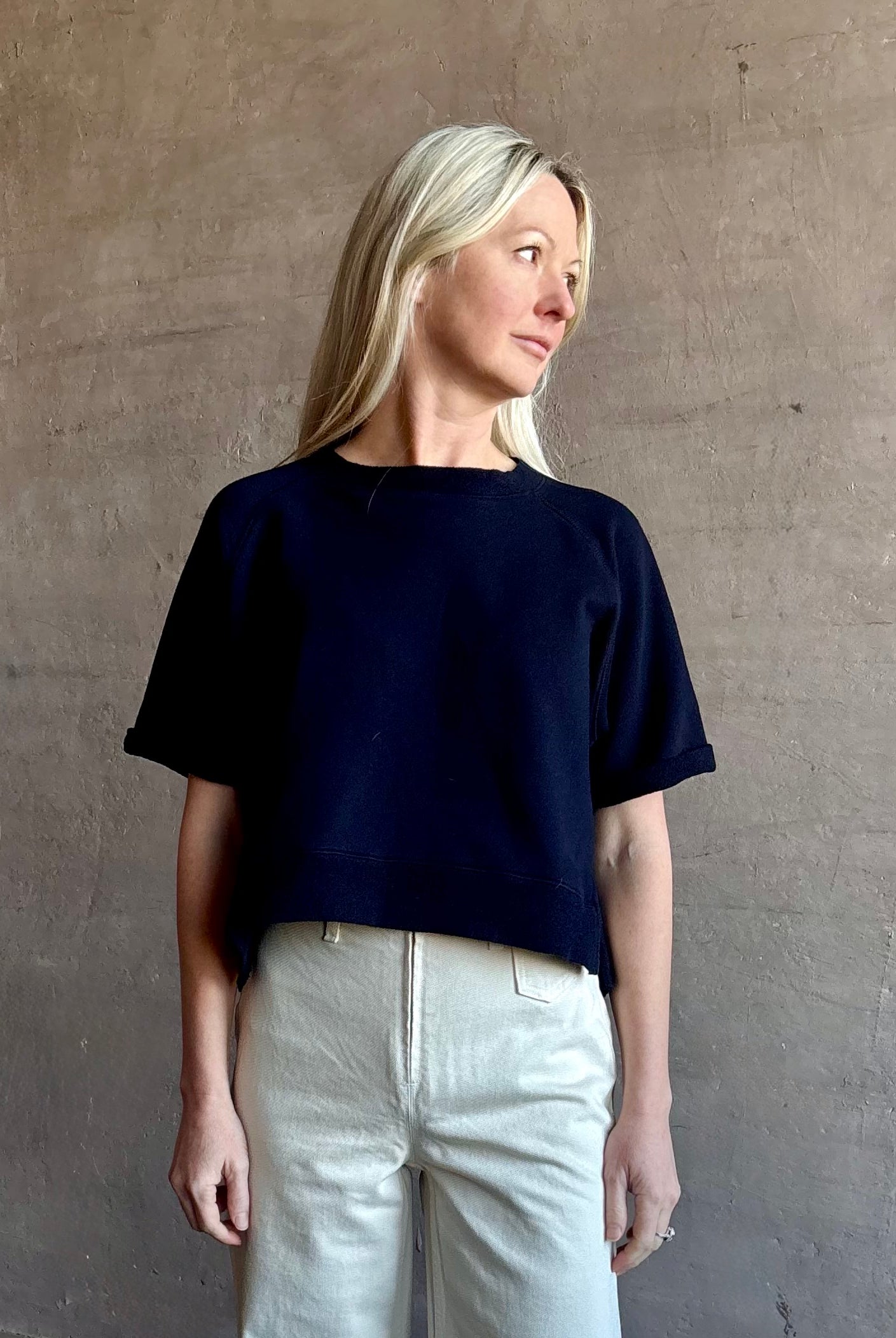 Mature woman waring the Slouchy Rolled Tee Top from TWP luxury women's designer tee rendered in a versatile navy blue and crafted from 100% cotton with short sleeves and crew neckline