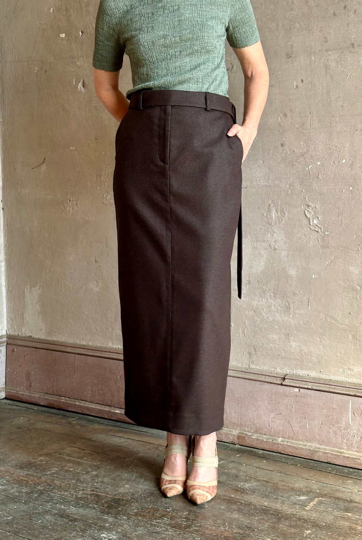 Mature woman wearing a long wool and cashmere chocolate brown pencil skirt from TWP with side pockets, tailored waist and American-made maxi